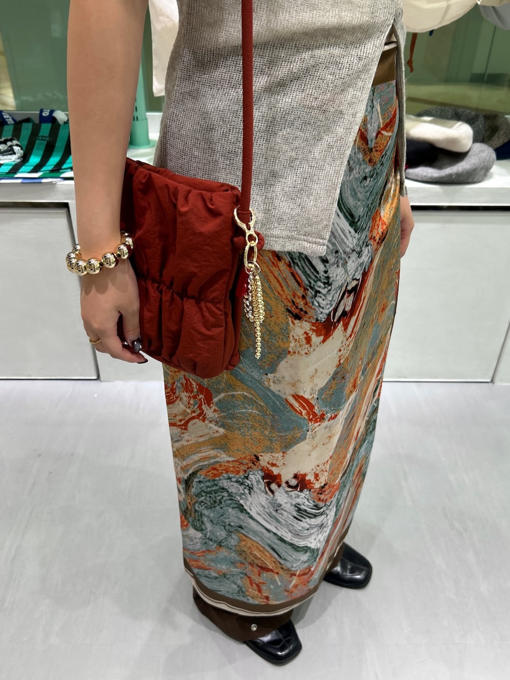 レッド系のショルダーバッグ、ブラック系のネックレス、ゴールド系のネックレスを着用したレディースの秋コーディネートの5枚目の写真