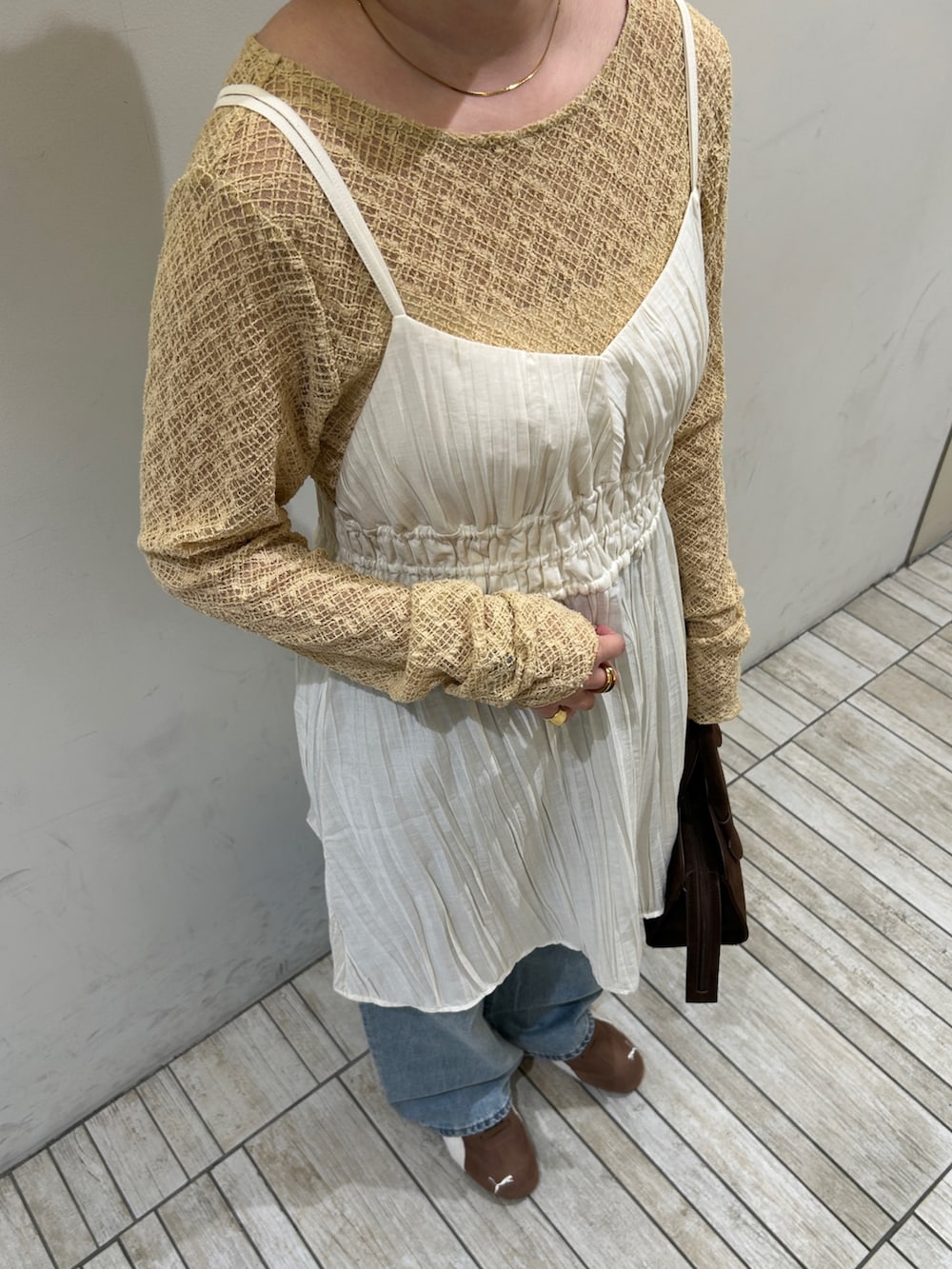 ブラウン系のスニーカー、ブルー系のデニムパンツ、ホワイト系のワンピースを着用したレディースの春コーディネートの4枚目の写真