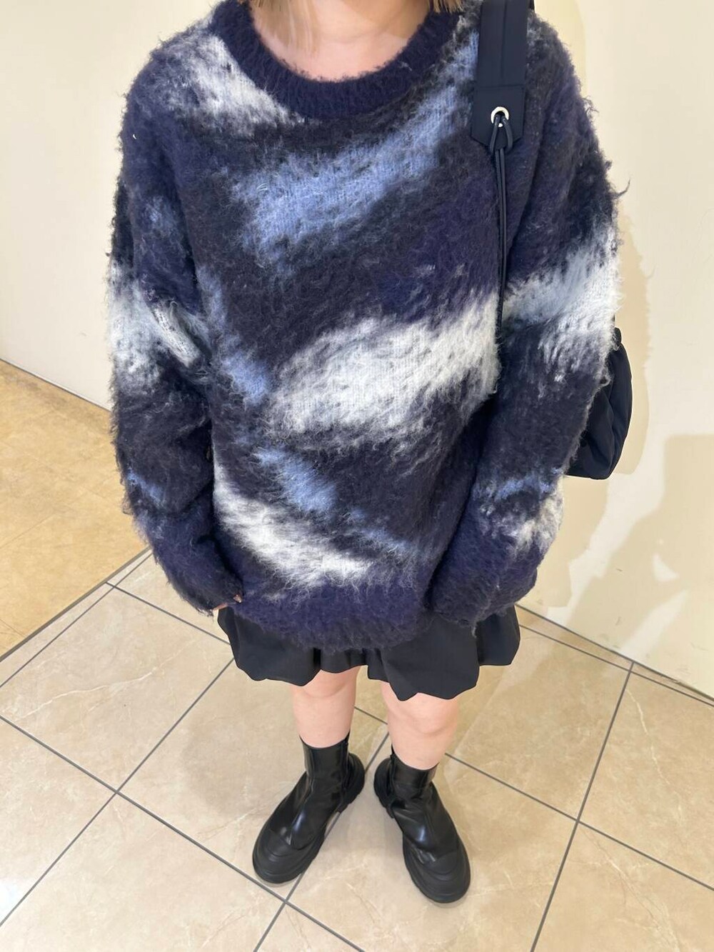 グレー系のスカート、ブラック系のブーツ、ブルー系のショルダーバッグを着用したレディースの秋コーディネートの6枚目の写真