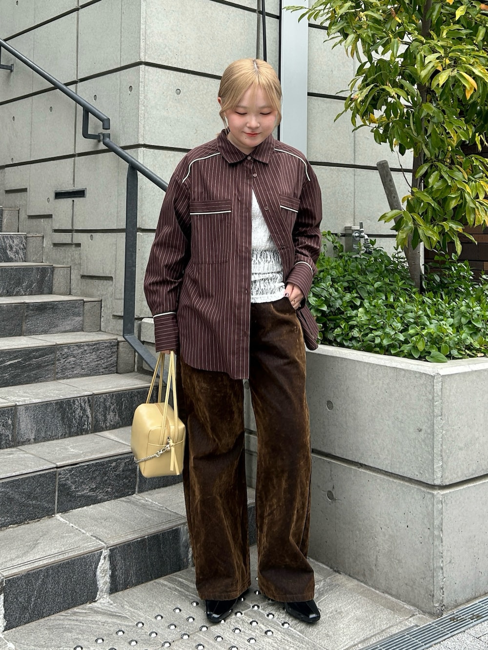 ブラウン系のシャツ/ブラウス、ホワイト系のTシャツ/カットソー、ブラウン系のデニムパンツを着用したレディースの春コーディネートの2枚目の写真