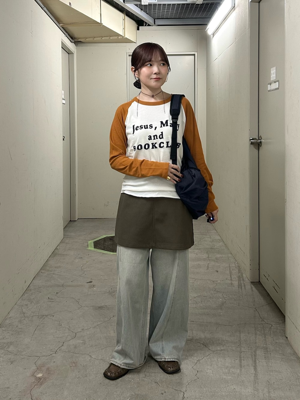 グリーン系のスカート、ブルー系のデニムパンツ、ブラウン系のローファーを着用したレディースの秋コーディネートの2枚目の写真