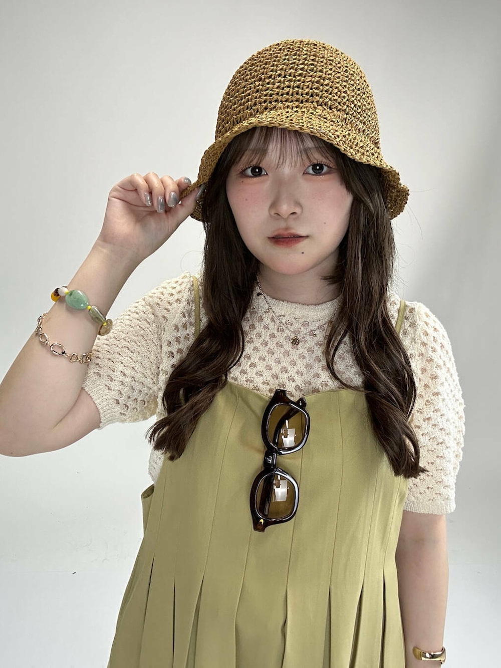 レッド系のハンドバッグ、ブルー系のデニムパンツ、ベージュ系のワンピースを着用したレディースの夏コーディネートの3枚目の写真