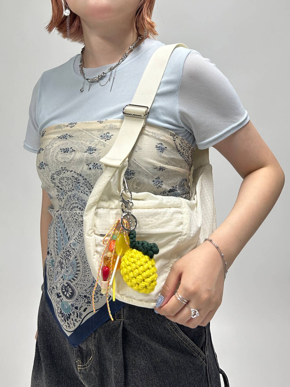 ホワイト系のショルダーバッグ、シルバー系のネックレス、シルバー系のイヤリングを着用したレディースの夏コーディネートの3枚目の写真