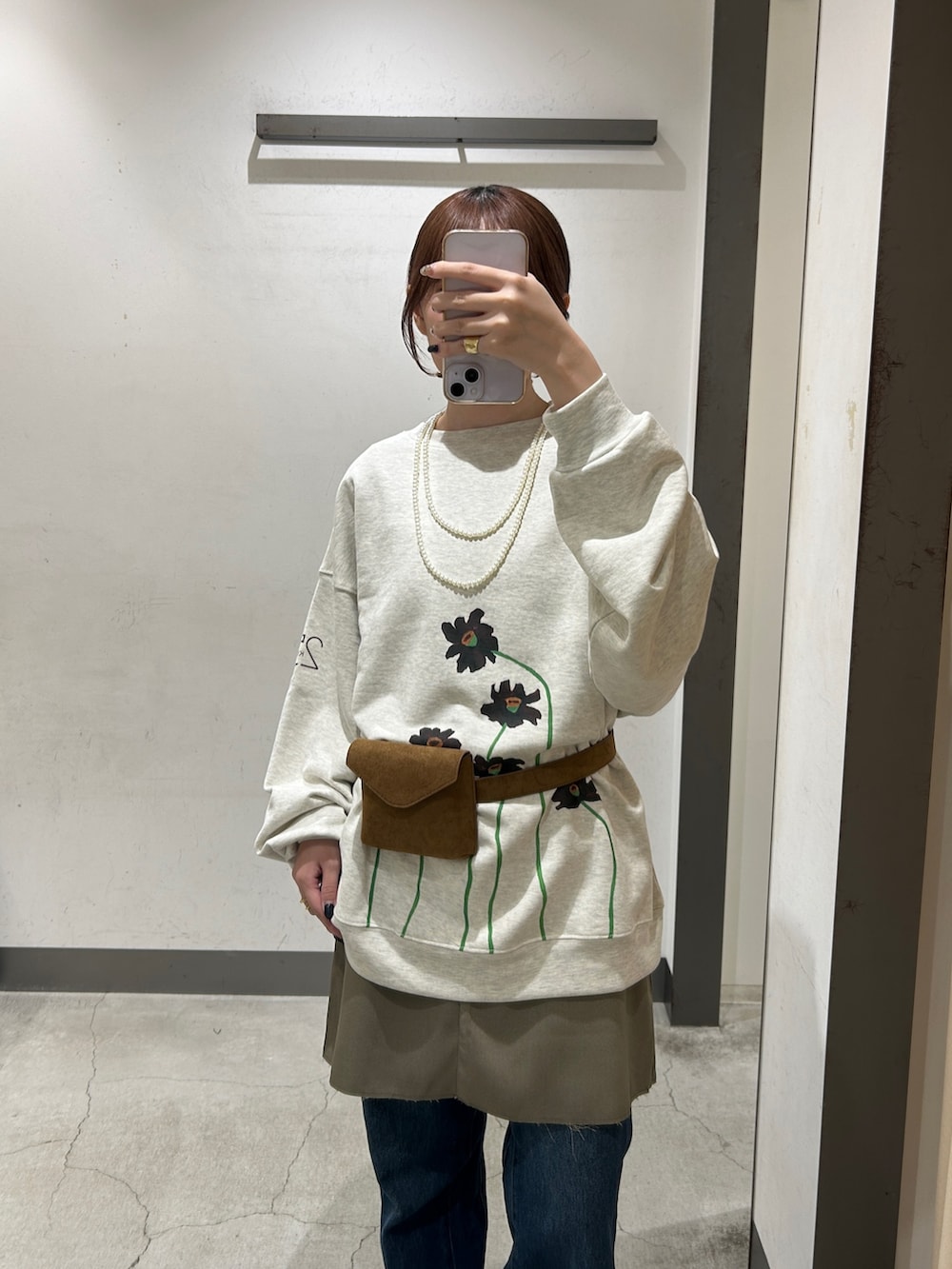 イエロー系のボディバッグ/ウエストポーチ、グレー系のスカート、ブルー系のデニムパンツを着用したレディースの秋コーディネートの3枚目の写真