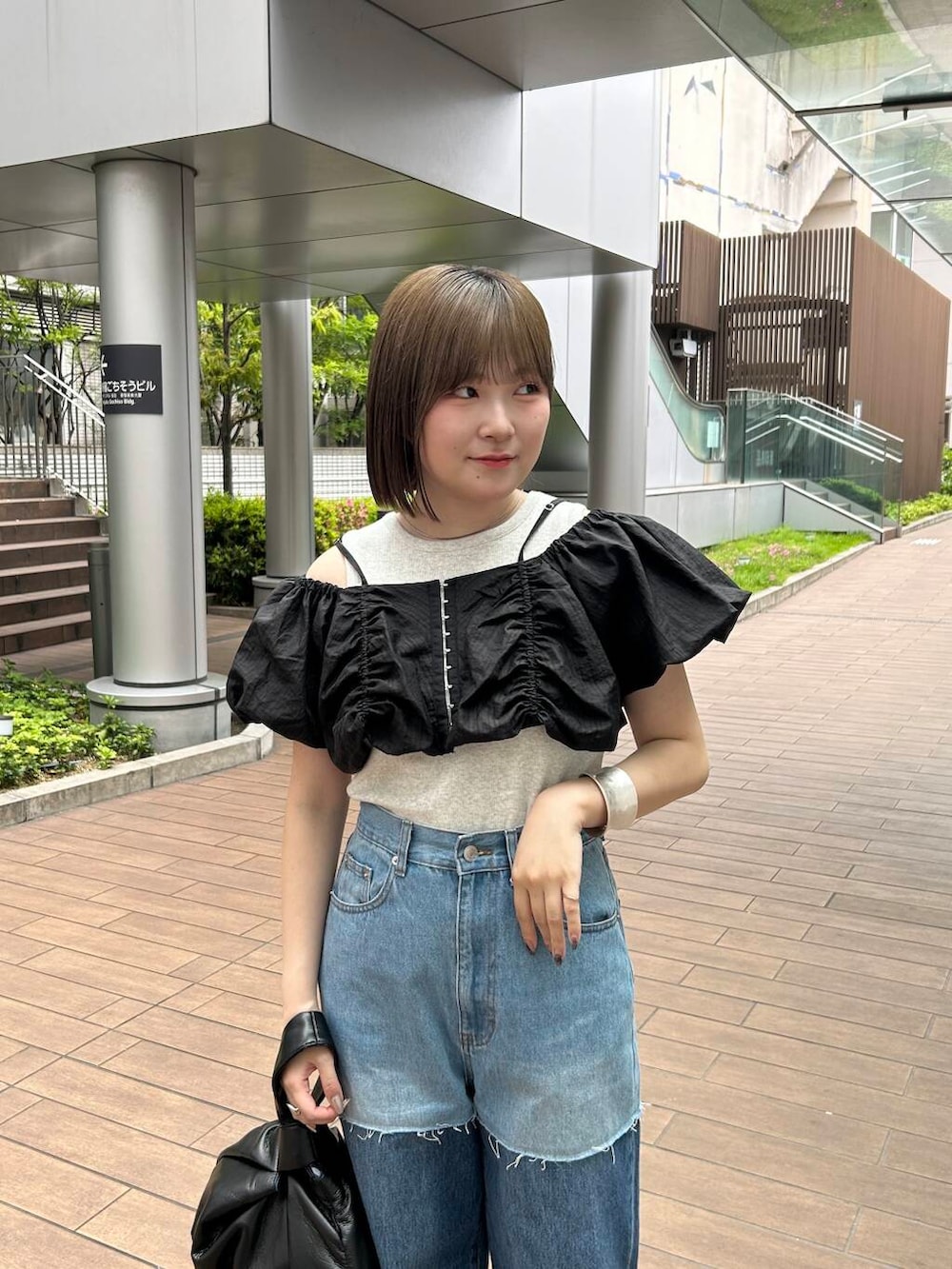 ブラック系のハンドバッグ、ブラック系のその他トップス、ブルー系のデニムパンツを着用したレディースの夏コーディネートの5枚目の写真