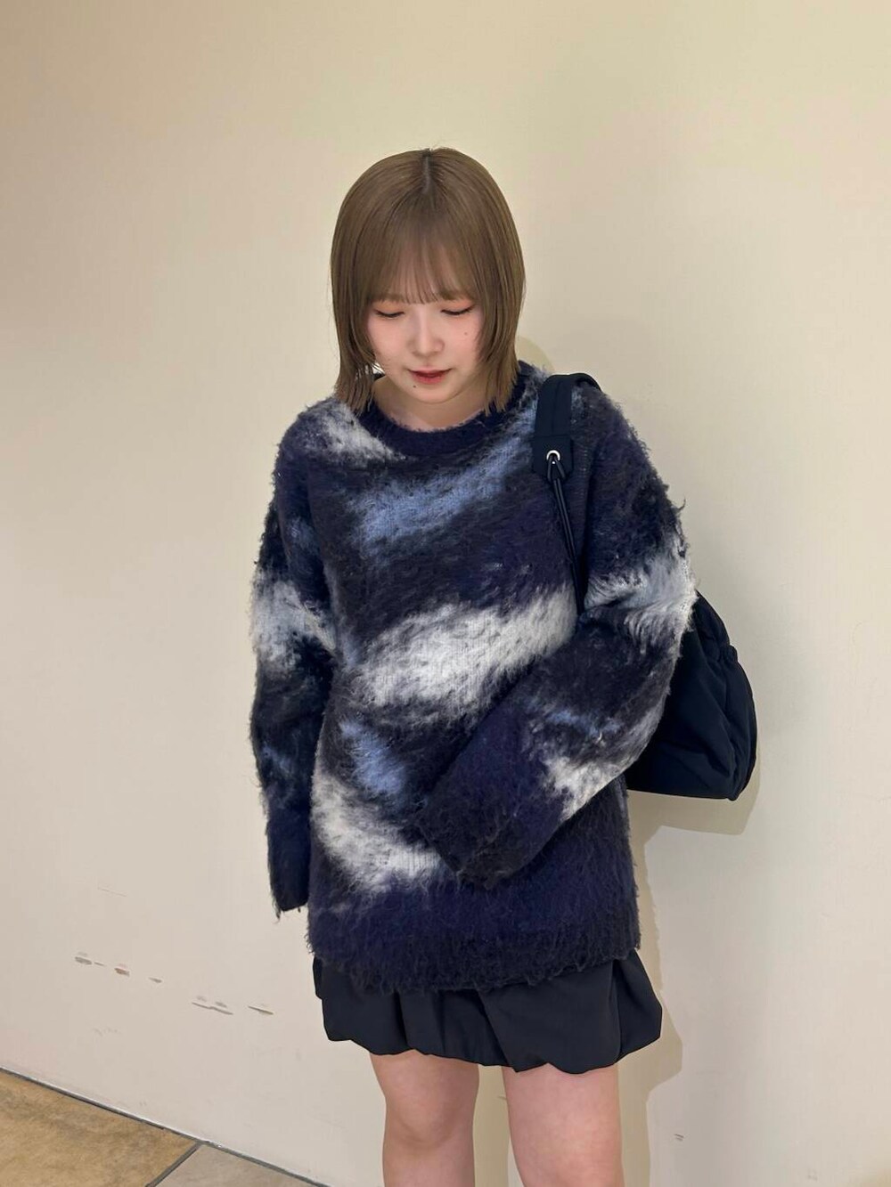 グレー系のスカート、ブラック系のブーツ、ブルー系のショルダーバッグを着用したレディースの秋コーディネートの4枚目の写真