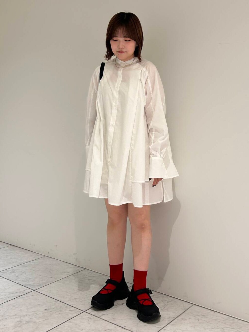 ブラック系のスニーカー、ブラウン系のベスト、ホワイト系のワンピースを着用したレディースの夏コーディネートの4枚目の写真