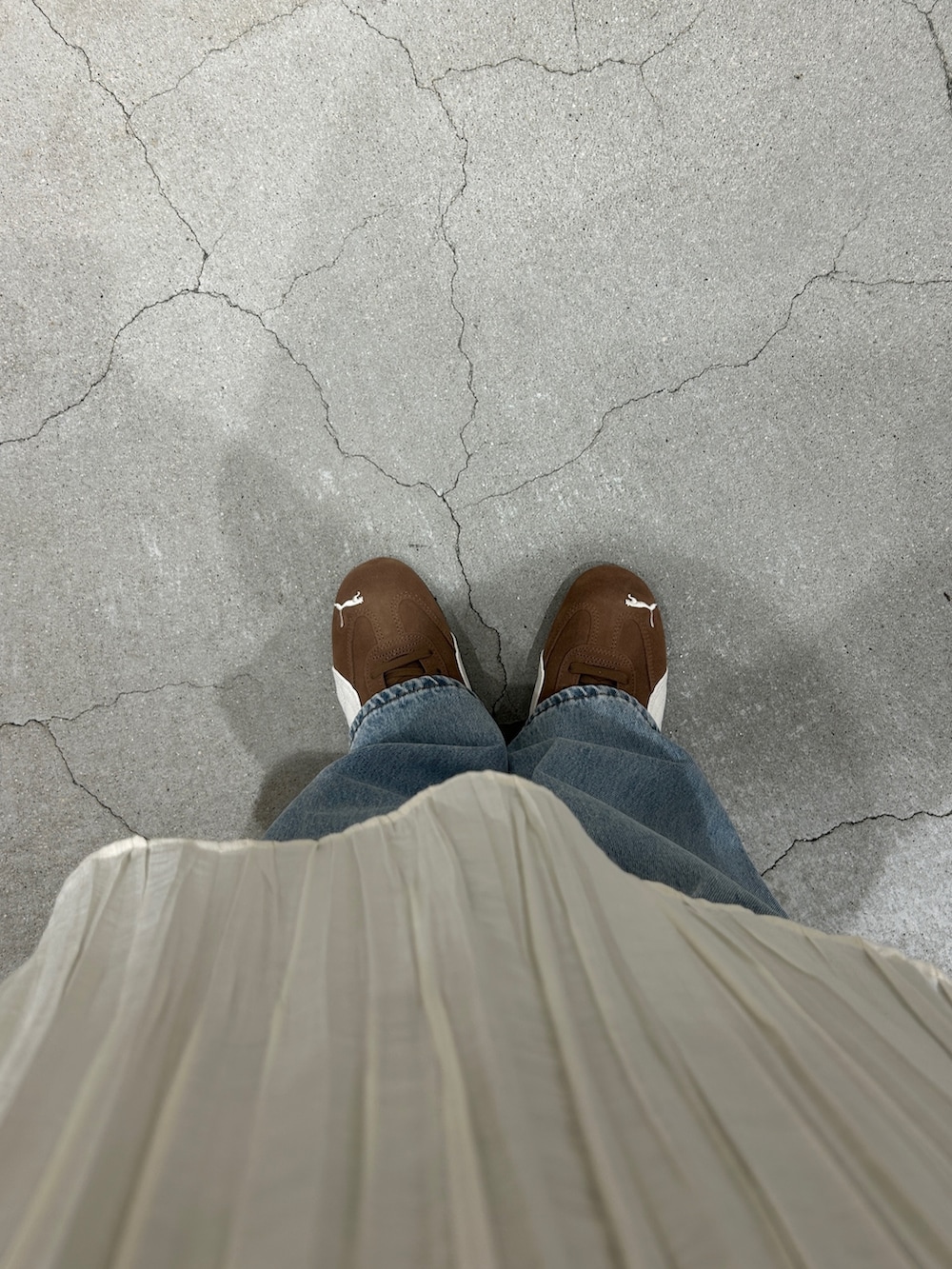 ブラウン系のスニーカー、ブルー系のデニムパンツ、ホワイト系のワンピースを着用したレディースの春コーディネートの5枚目の写真