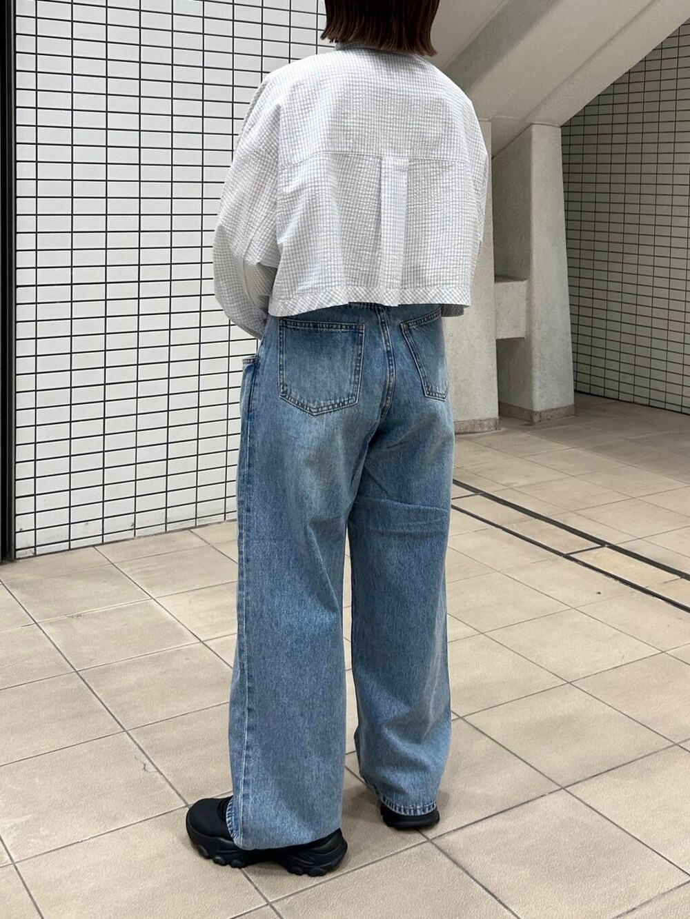 ブルー系のデニムパンツ、ブラック系のスニーカー、レッド系のショルダーバッグを着用したレディースの冬コーディネートの3枚目の写真