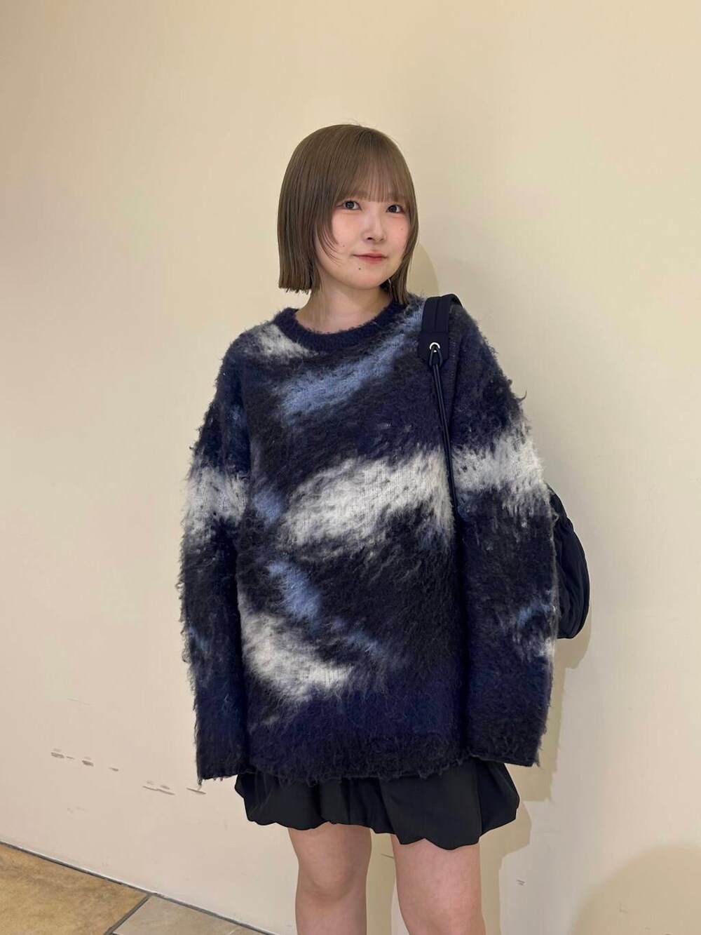 グレー系のスカート、ブラック系のブーツ、ブルー系のショルダーバッグを着用したレディースの秋コーディネートの5枚目の写真