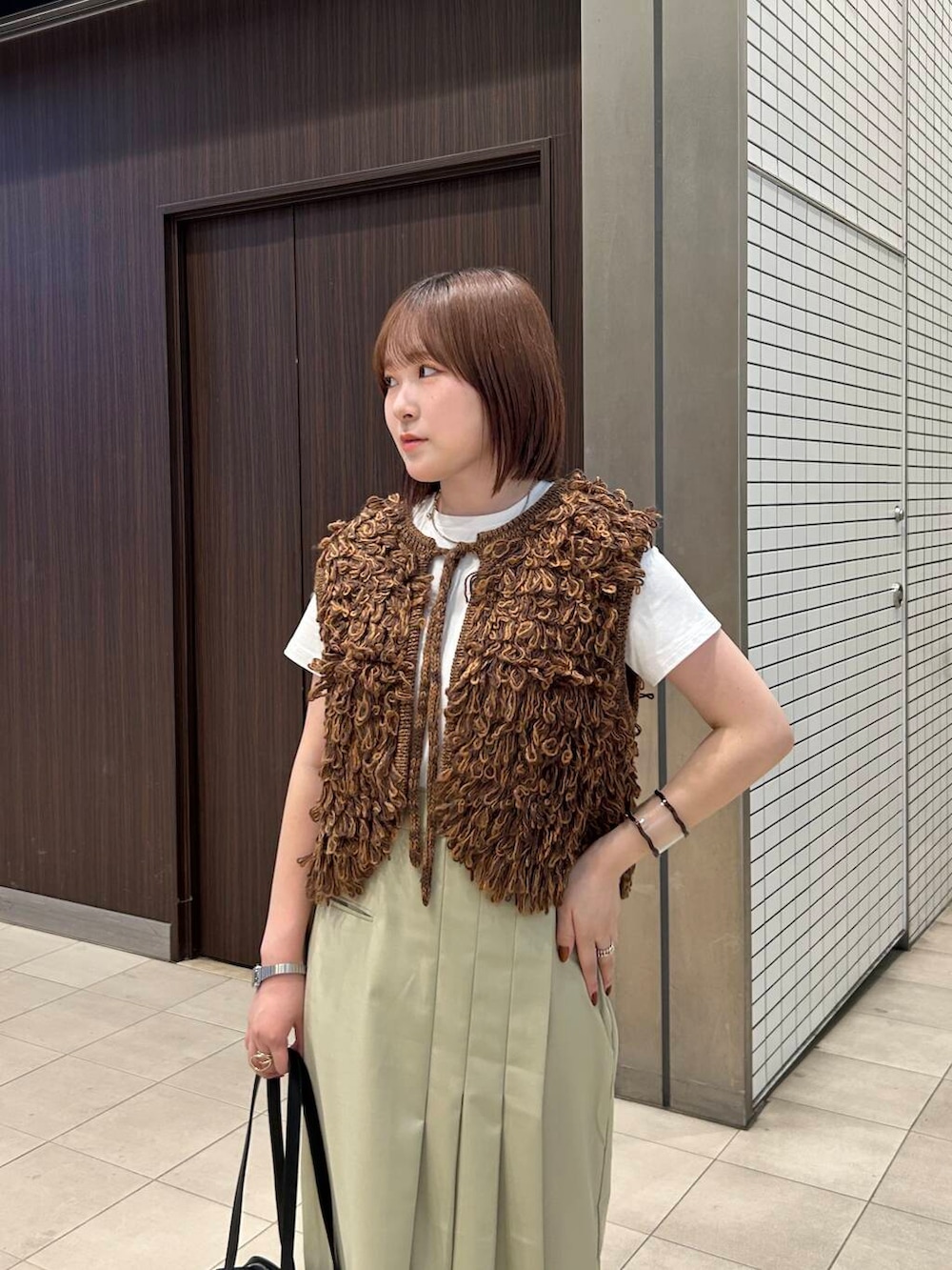 ホワイト系のTシャツ/カットソー、ブラウン系のベスト、ブラック系のボストンバッグを着用したレディースの夏コーディネートの4枚目の写真