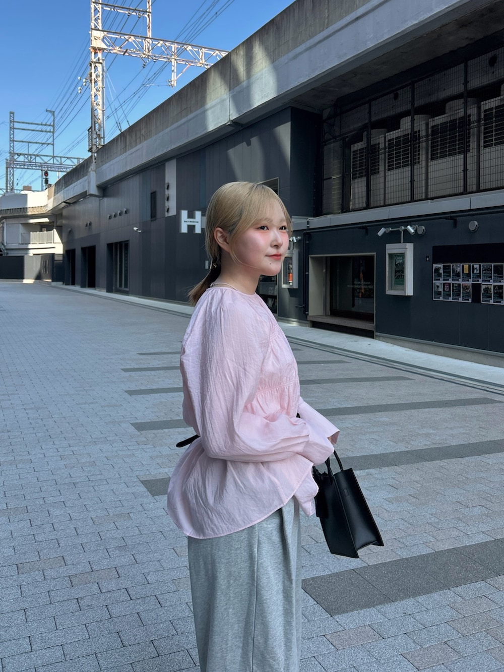 ピンク系のシャツ/ブラウス、グレー系のその他パンツ、ブラック系のハンドバッグを着用したレディースの春コーディネートの4枚目の写真