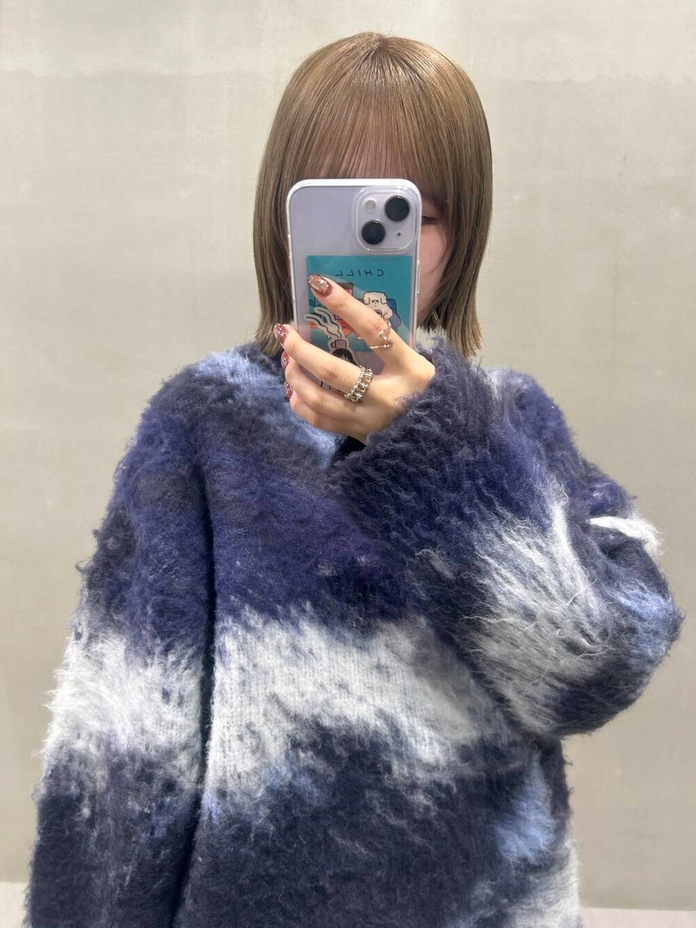 グレー系のスカート、ブラック系のブーツ、ブルー系のショルダーバッグを着用したレディースの秋コーディネートの7枚目の写真