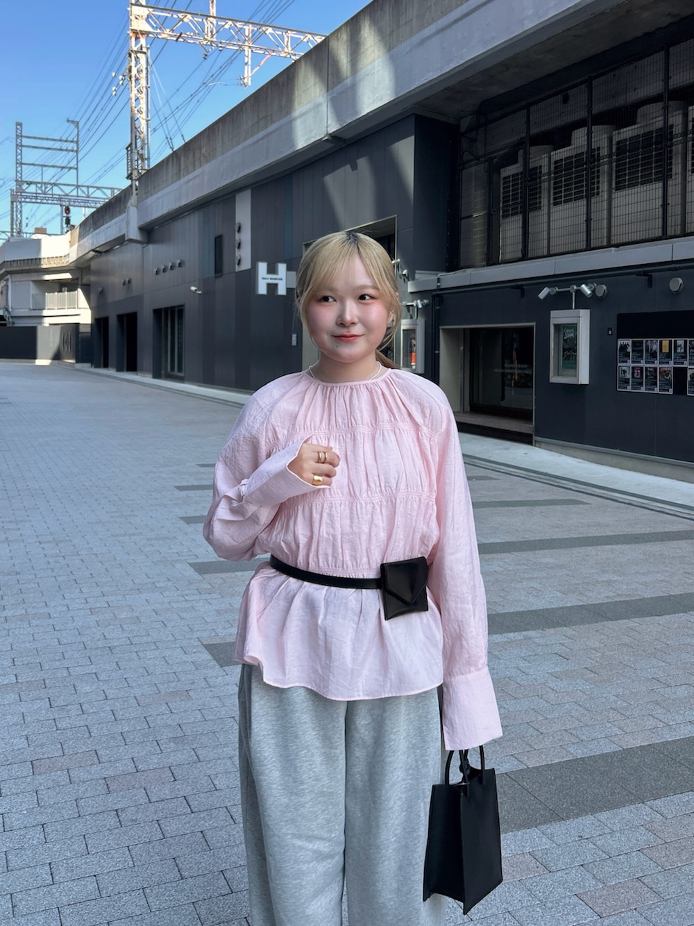 ピンク系のシャツ/ブラウス、グレー系のその他パンツ、ブラック系のハンドバッグを着用したレディースの春コーディネートの3枚目の写真