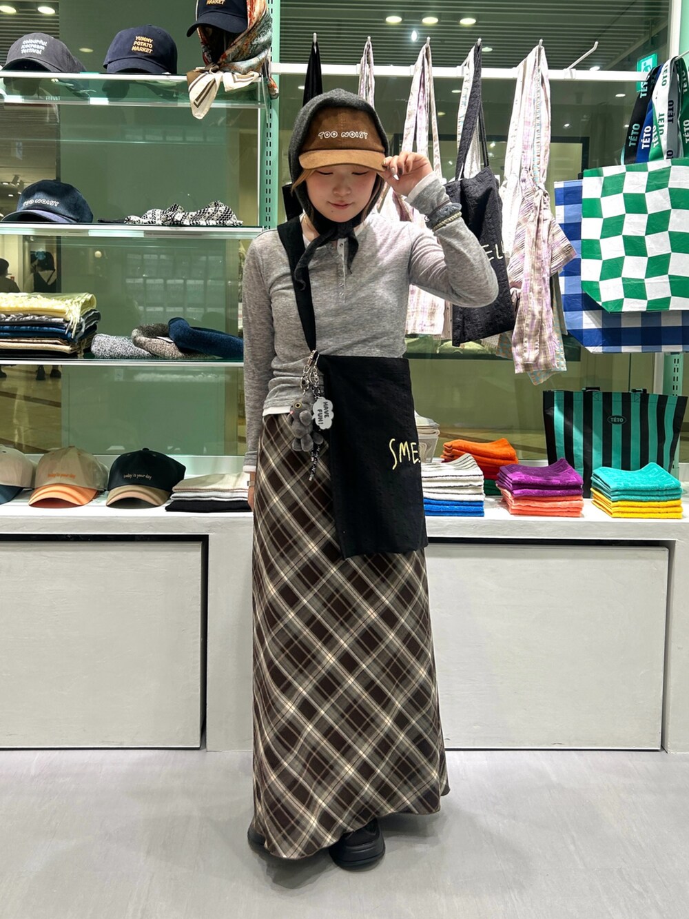 ブラック系のスニーカー、ブラウン系のスカート、ブラック系のショルダーバッグを着用したレディースの秋コーディネートの2枚目の写真