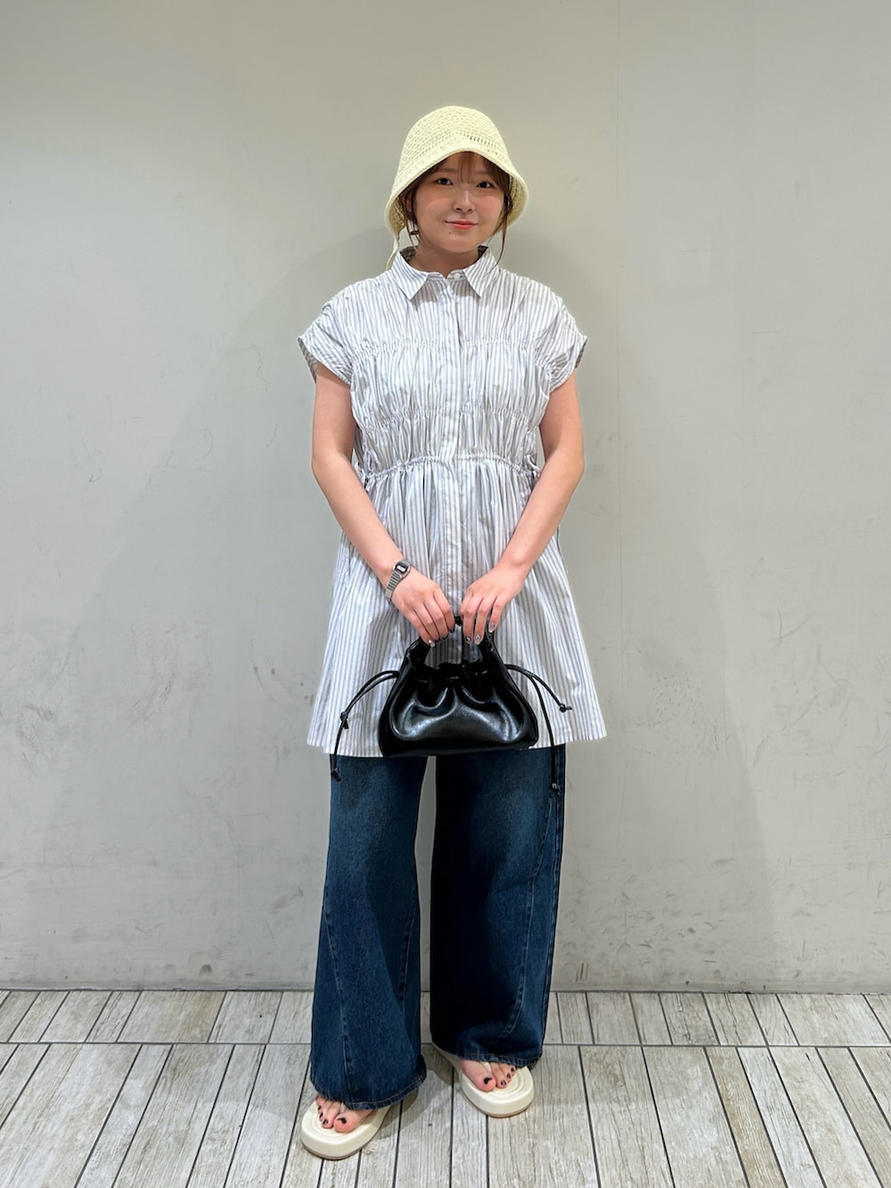 ホワイト系のワンピース、ブルー系のデニムパンツ、ホワイト系のサンダルを着用したレディースの夏コーディネートの2枚目の写真