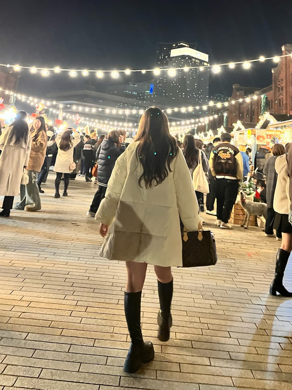 ブラック系のブーツ、ホワイト系のダウンジャケット/コート、ブラウン系のボストンバッグを着用したレディースの冬コーディネートの2枚目の写真