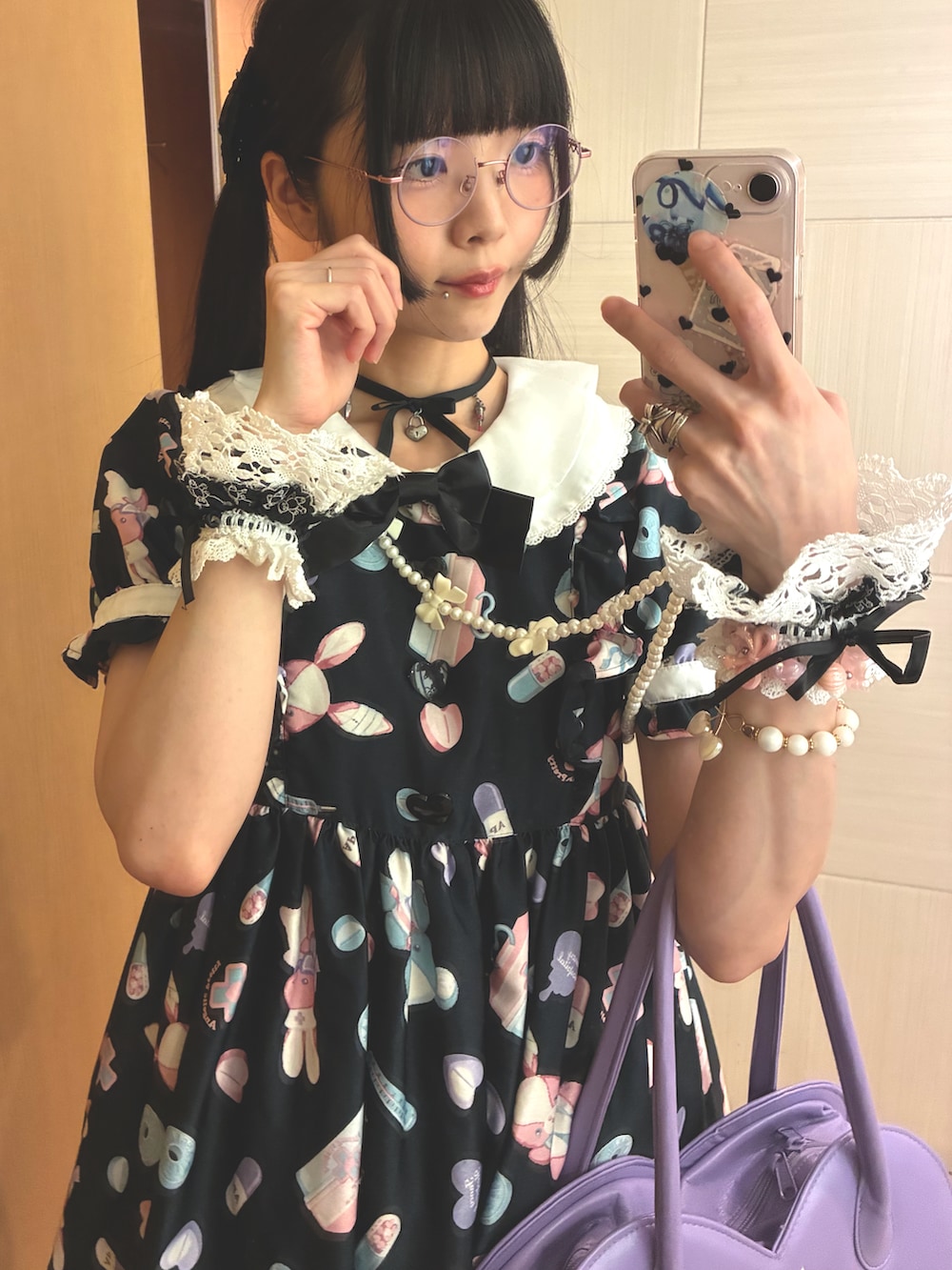 パープル系のショルダーバッグ、ブラック系のワンピース、ブラック系のパンプスを着用したレディースの夏コーディネートの2枚目の写真