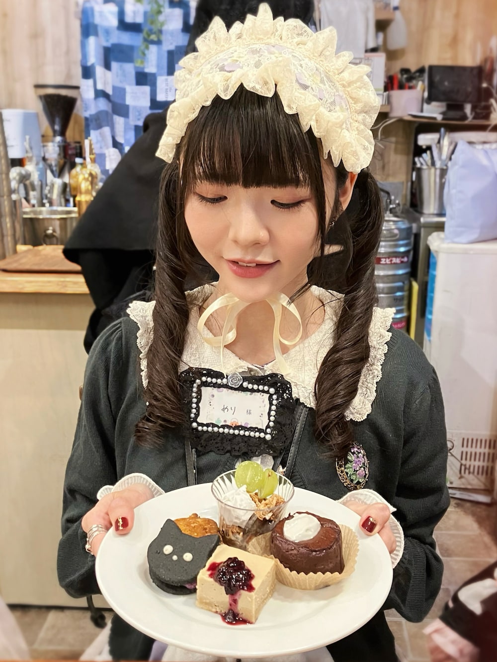 グリーン系のカーディガン/ボレロ、ホワイト系のワンピース、ブラウン系のパンプスを着用したレディースの秋コーディネートの2枚目の写真