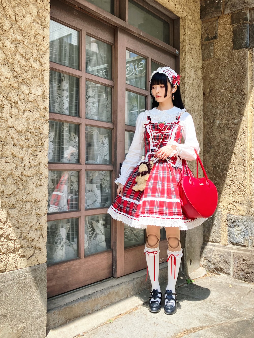 ブラック系のパンプス、ホワイト系のシャツ/ブラウス、レッド系のジャンパースカートを着用したレディースの春コーディネートの2枚目の写真