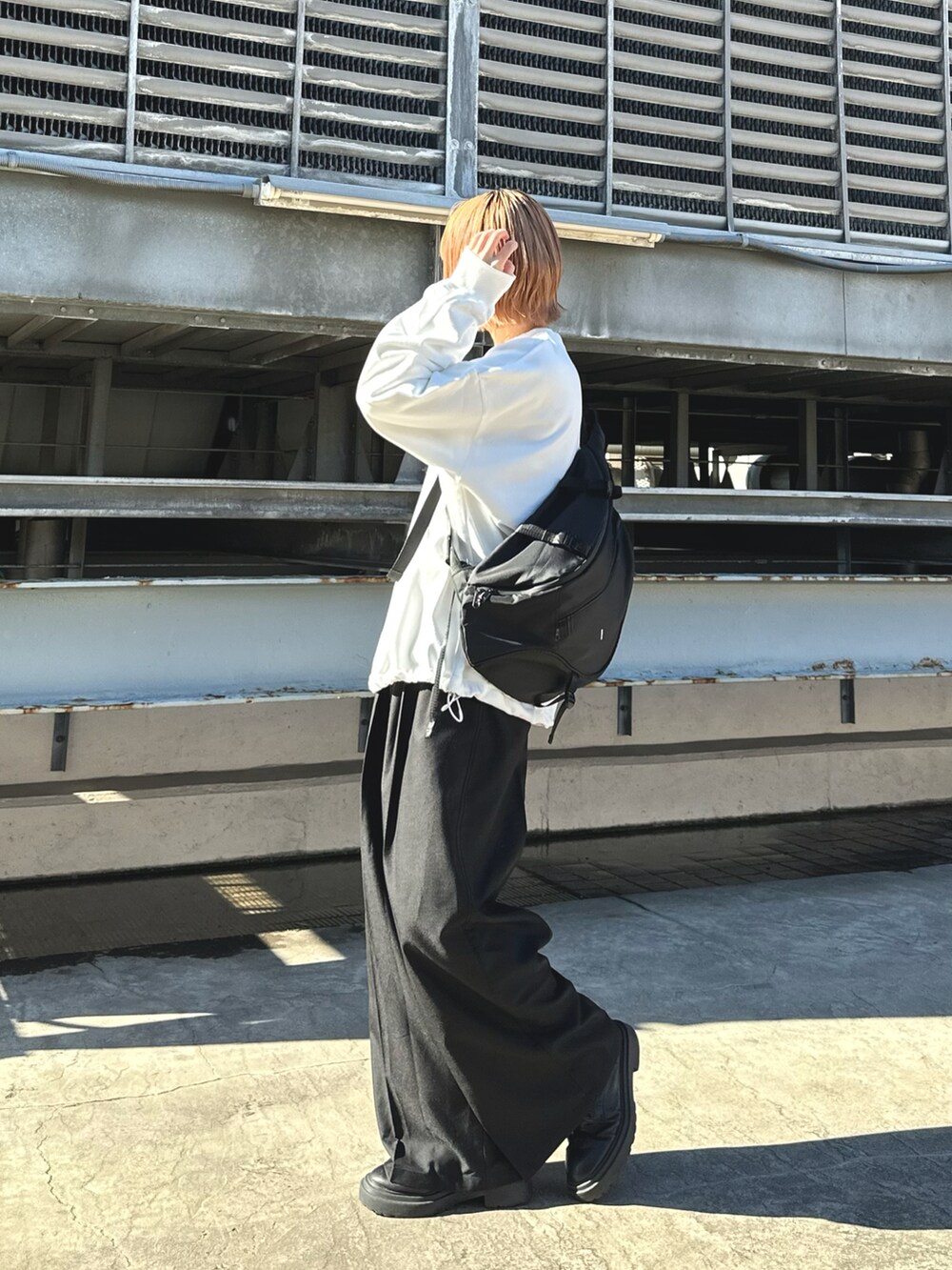 ホワイト系のスウェット、ブラック系のボディバッグ/ウエストポーチを着用したレディースの冬コーディネートの2枚目の写真