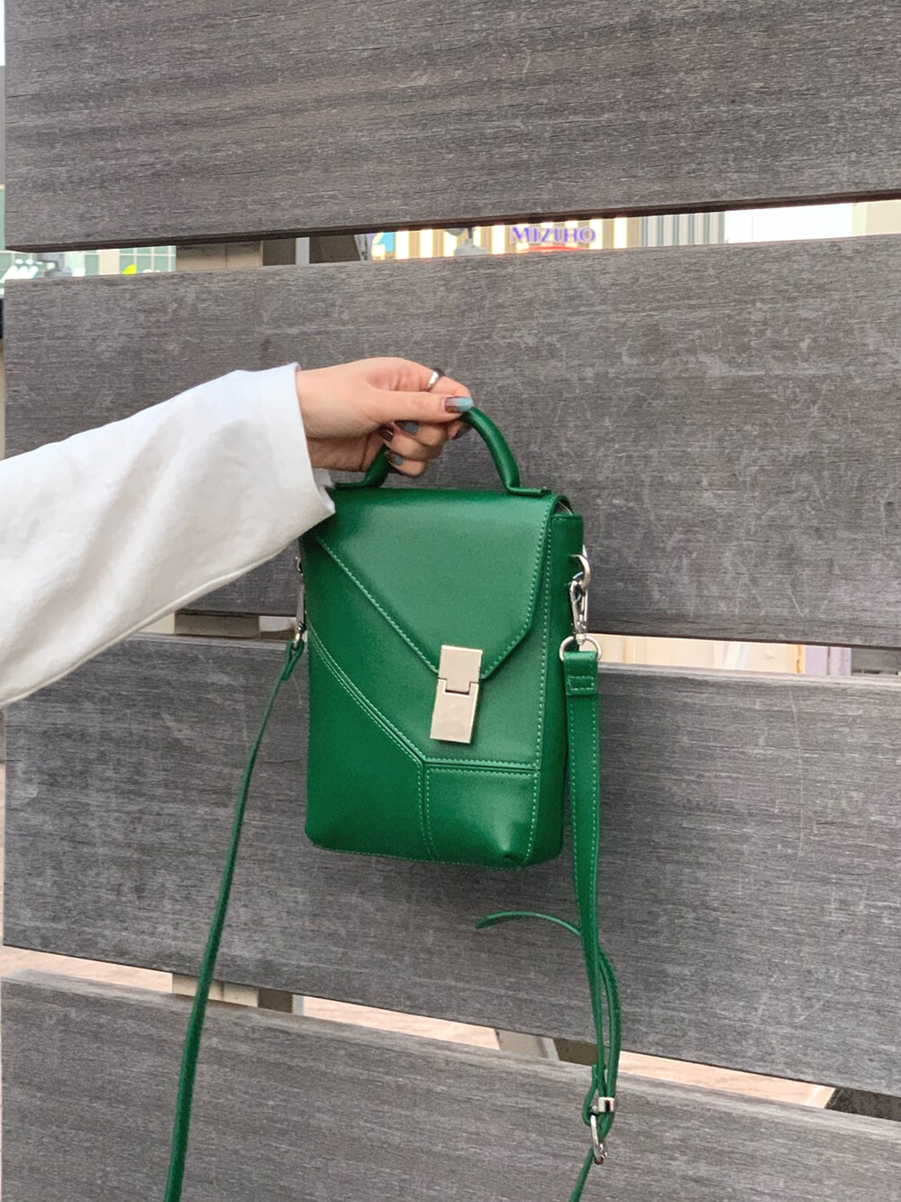 ブラック系のベスト、グリーン系のショルダーバッグを着用したレディースの冬コーディネートの2枚目の写真