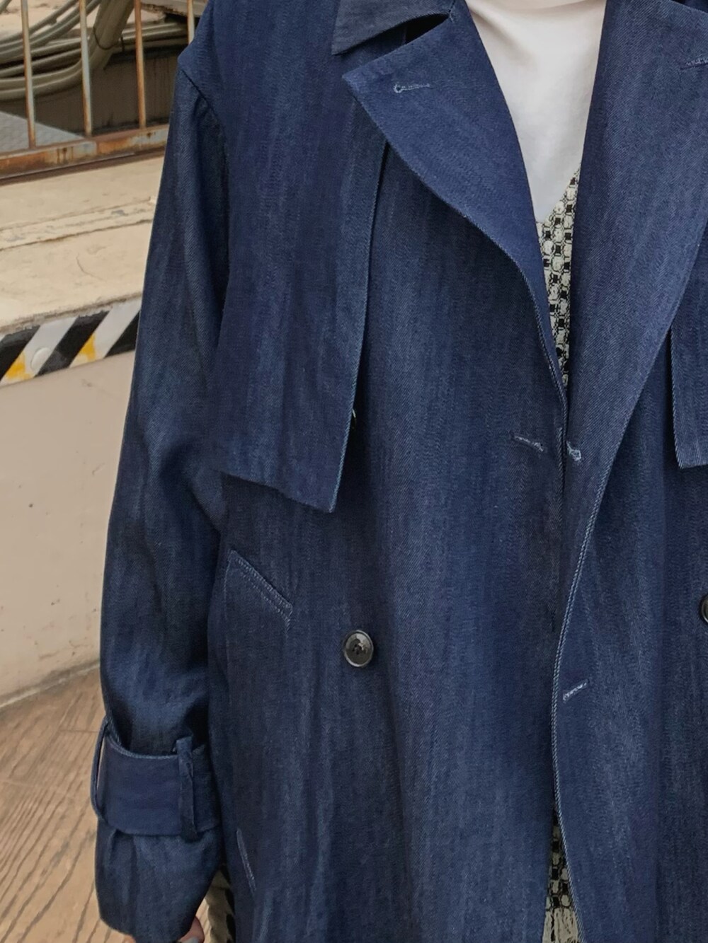 ブルー系のトレンチコート、ブラック系のベストを着用したレディースの冬コーディネートの3枚目の写真