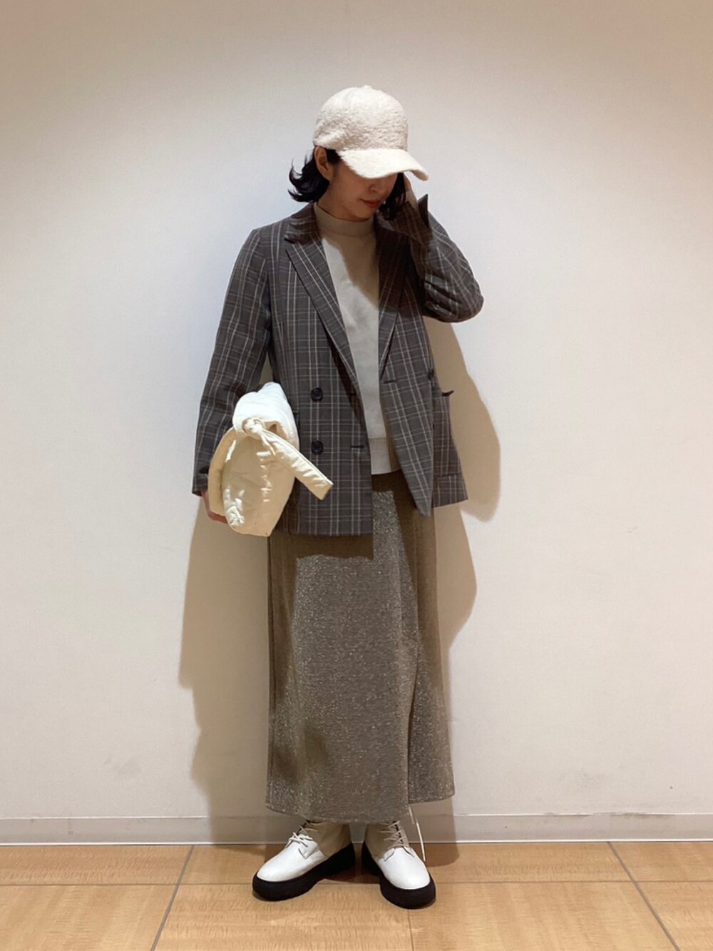 グレー系のノーカラージャケット、ホワイト系のブーツ、ベージュ系のスカートを着用したレディースの秋コーディネートの2枚目の写真