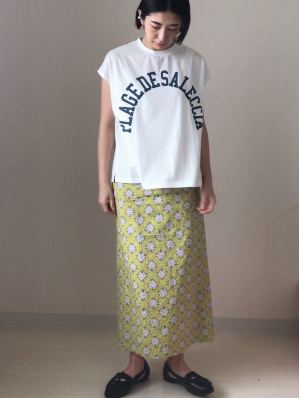 ブラック系のドレスシューズ、ホワイト系のTシャツ/カットソー、イエロー系のスカートを着用したレディースの春コーディネートの2枚目の写真