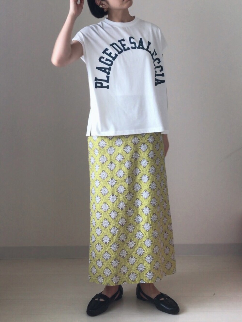 ブラック系のドレスシューズ、ホワイト系のTシャツ/カットソー、イエロー系のスカートを着用したレディースの春コーディネートの4枚目の写真
