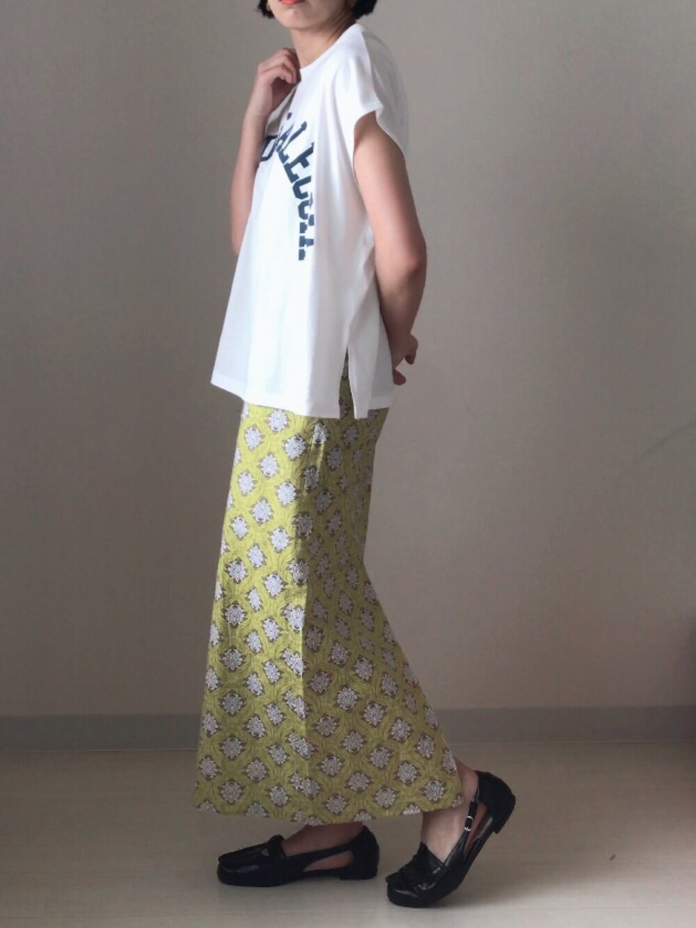 ブラック系のドレスシューズ、ホワイト系のTシャツ/カットソー、イエロー系のスカートを着用したレディースの春コーディネートの3枚目の写真