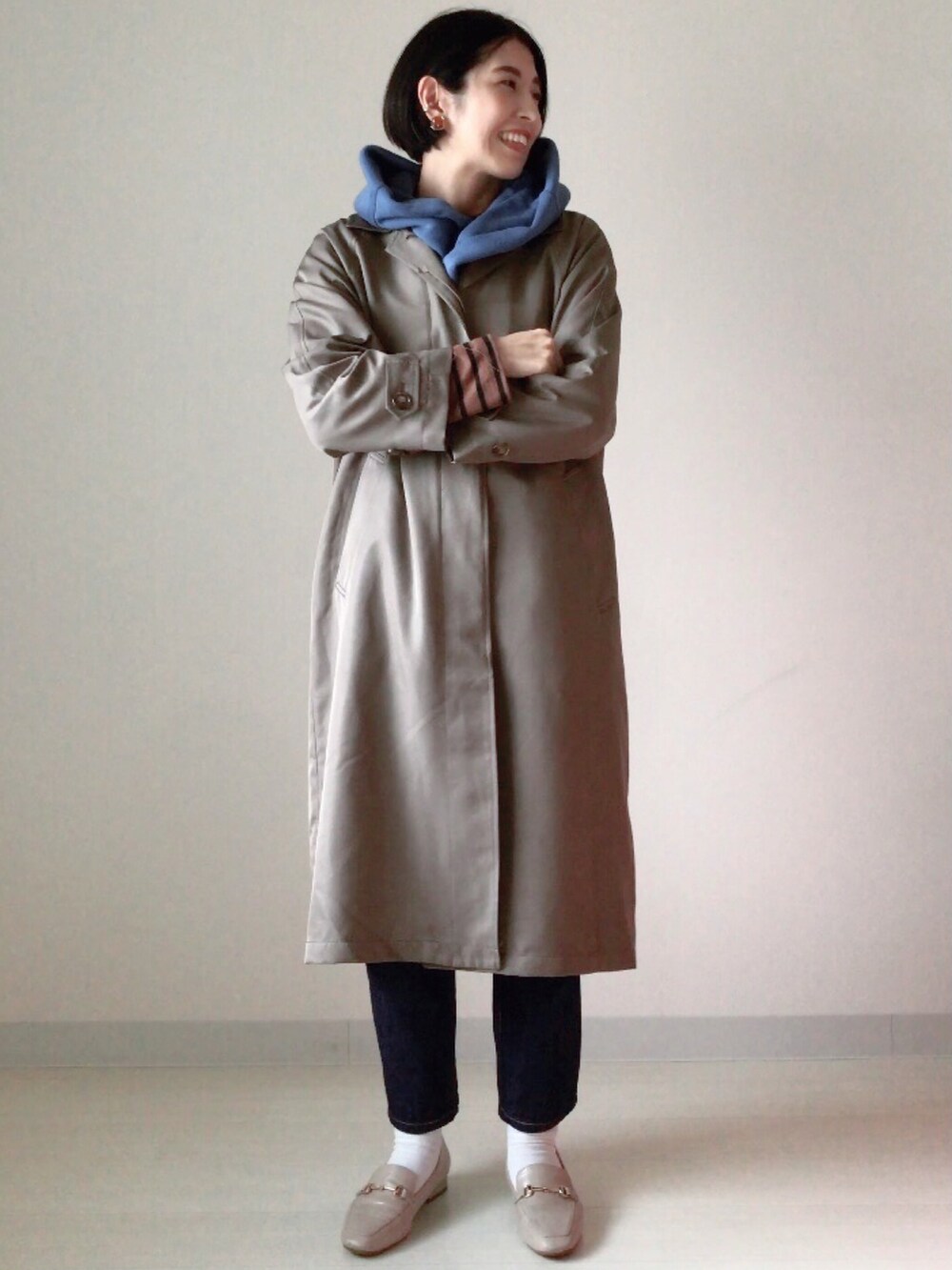 ブルー系のニット/セーター、ブラウン系のステンカラーコート、ブラウン系のニット/セーターを着用したレディースの秋コーディネートの2枚目の写真