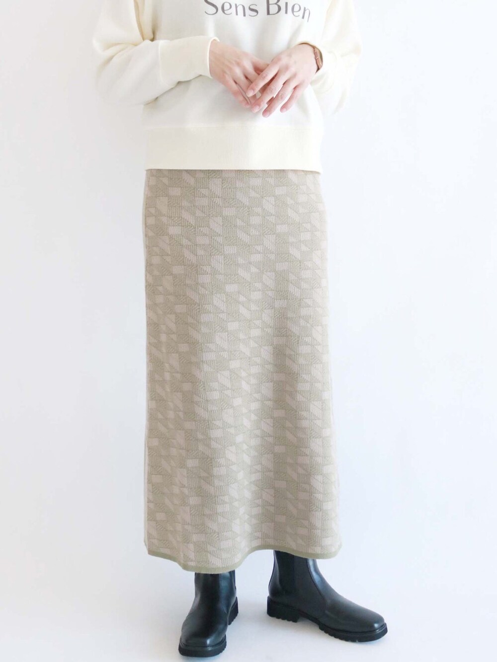 ホワイト系のスウェット、グリーン系のスカート、ブラック系のブーツを着用したレディースの冬コーディネートの2枚目の写真