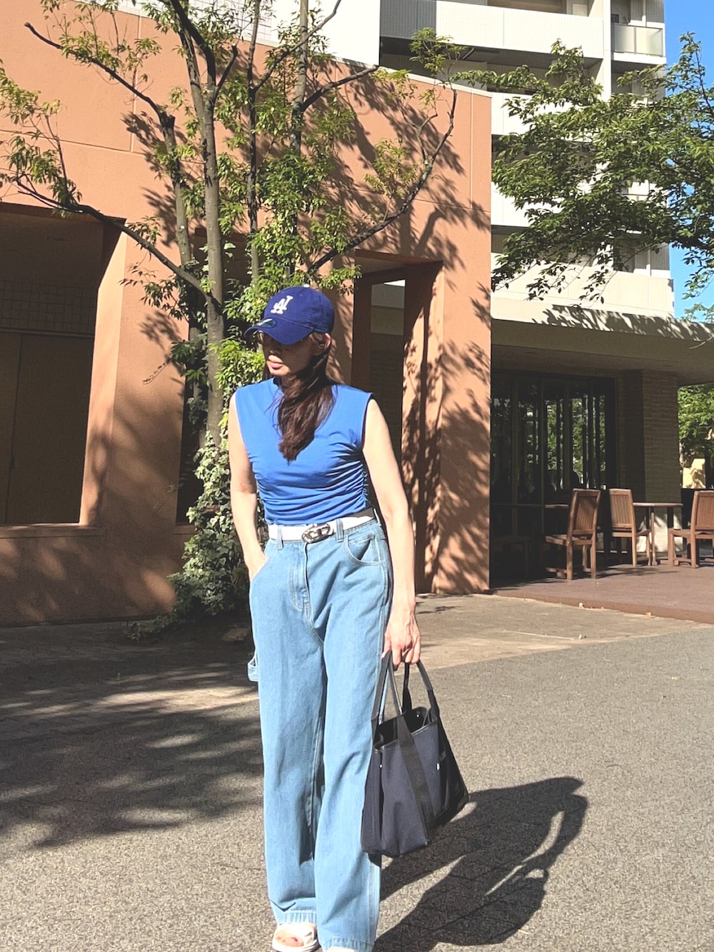 ブルー系のデニムパンツ、ブルー系のキャップ、ホワイト系のベルトを着用したレディースの夏コーディネートの2枚目の写真