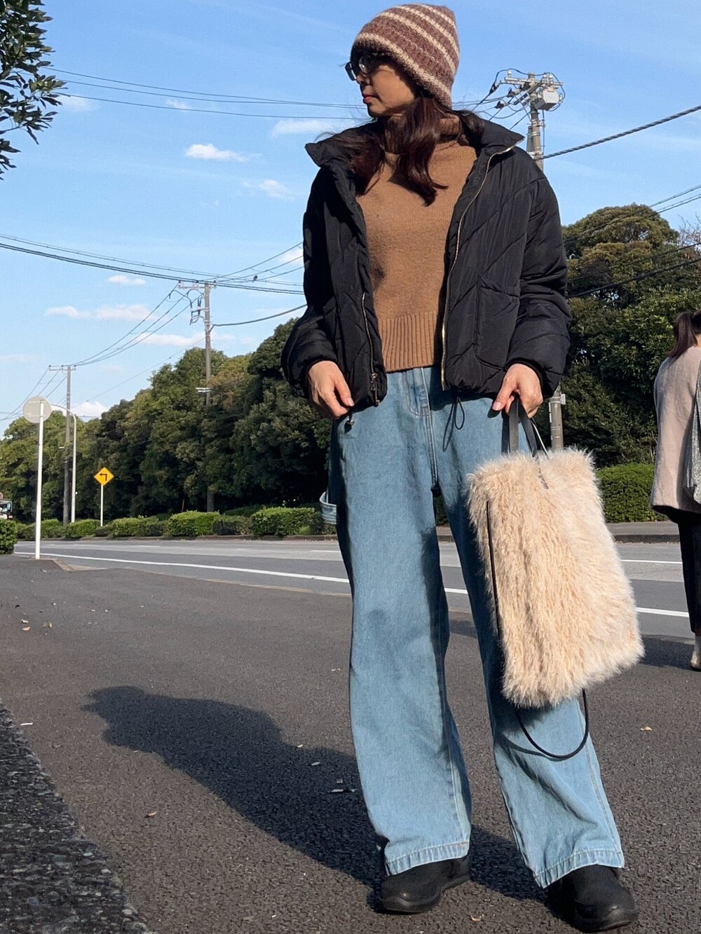 ブルー系のデニムパンツ、ブラック系のジャケット/アウター、ブラック系のスニーカーを着用したレディースの秋コーディネートの2枚目の写真