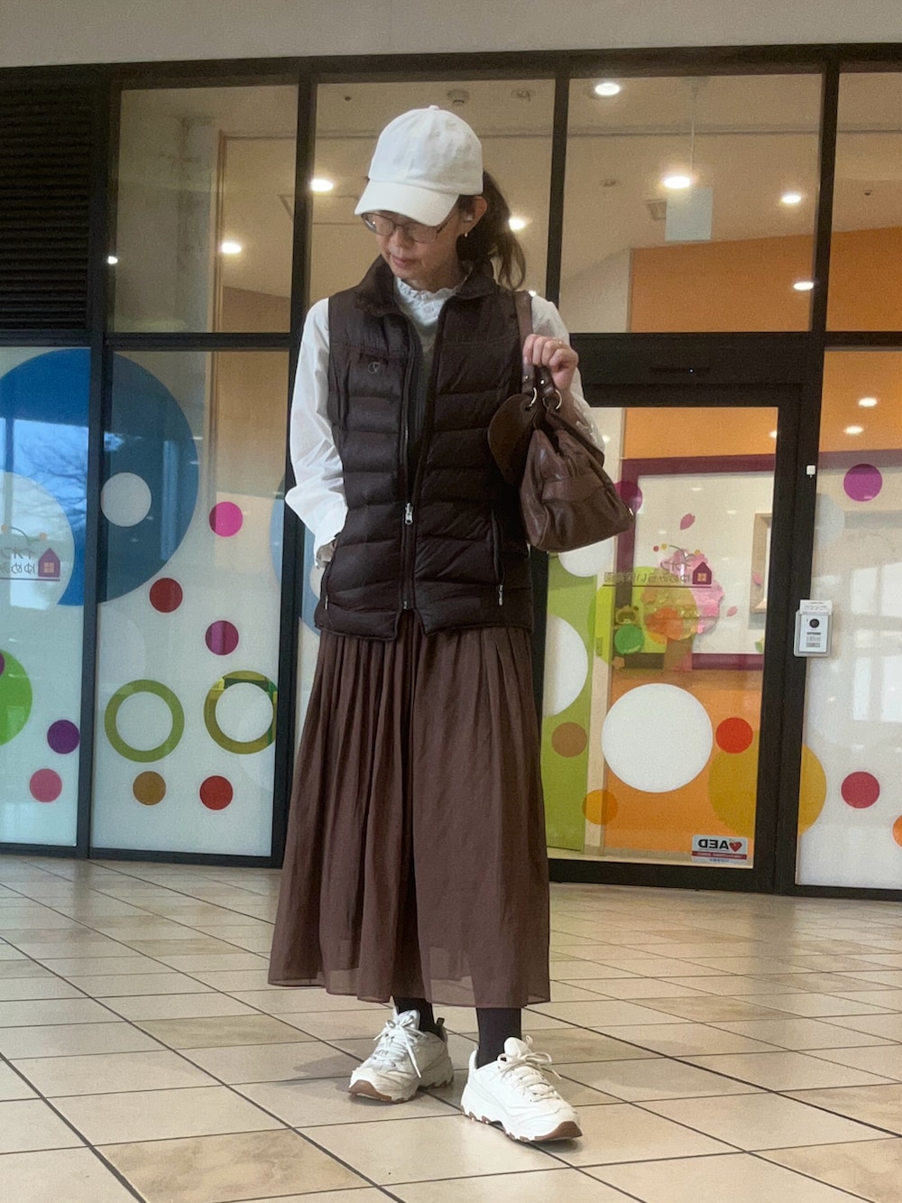 ホワイト系のシャツ/ブラウス、ホワイト系のスニーカー、ブラウン系のスカートを着用したレディースの春コーディネートの2枚目の写真