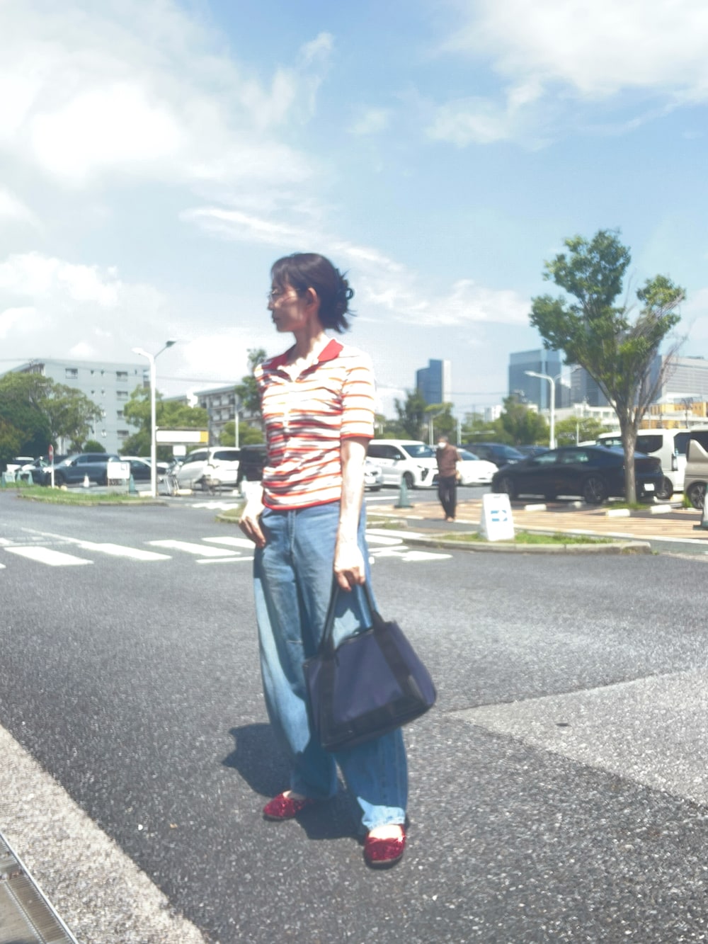 ブルー系のデニムパンツ、レッド系のポロシャツ、レッド系のバレエシューズを着用したレディースの夏コーディネートの2枚目の写真