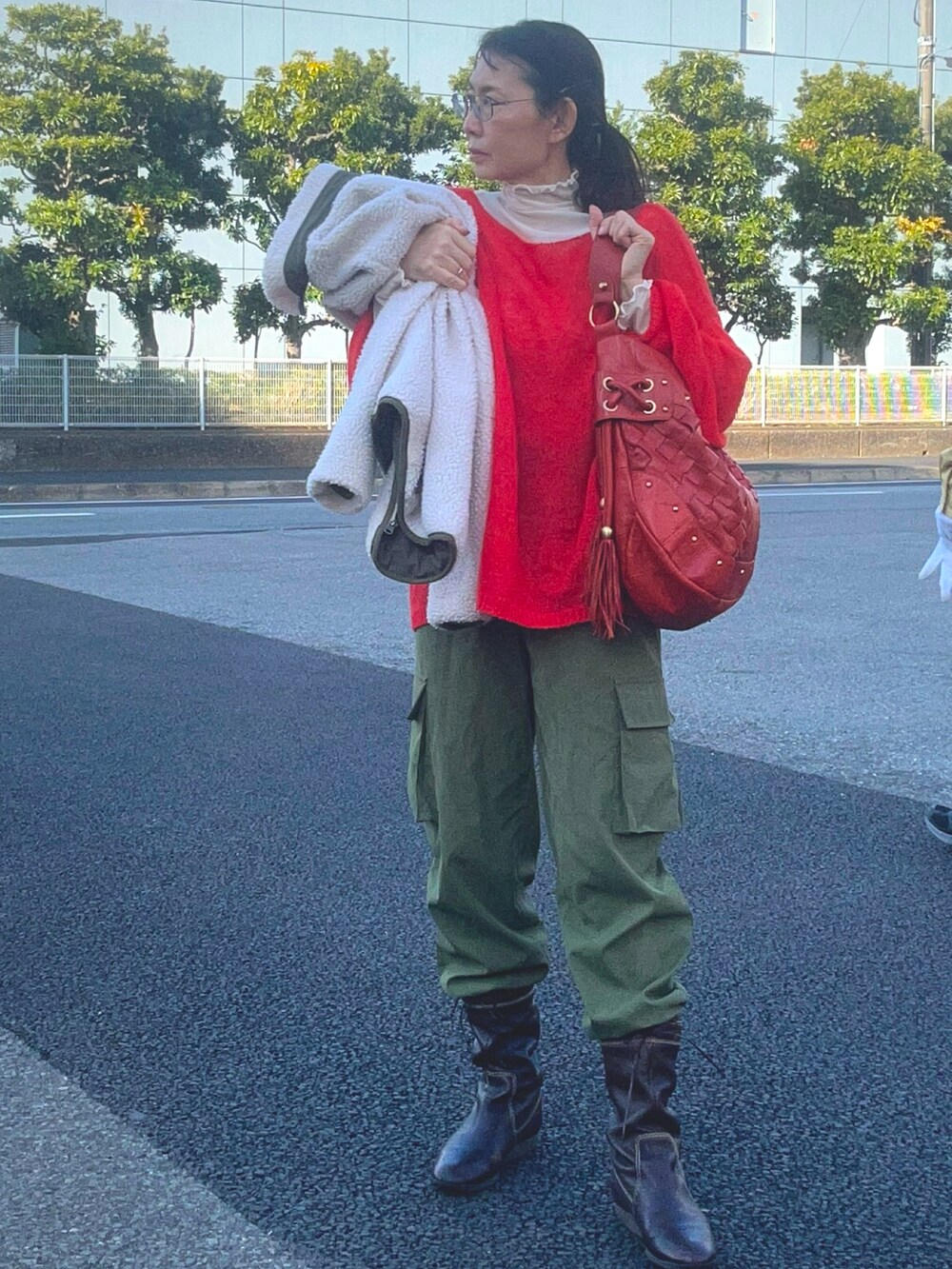 オレンジ系のニット/セーター、ブラウン系のブーツ、ベージュ系のその他アウターを着用したレディースの春コーディネートの3枚目の写真