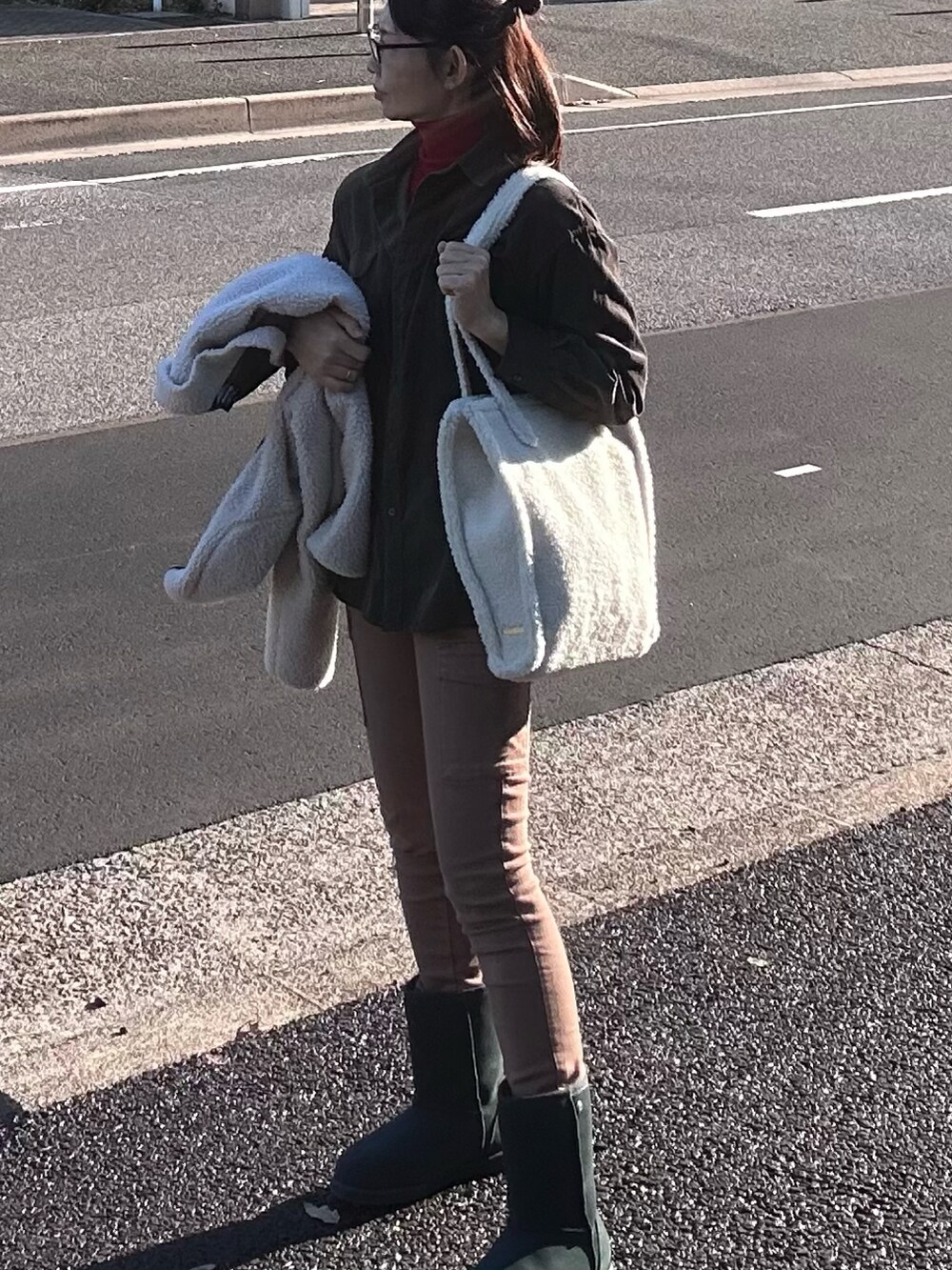 ブラウン系のチノパンツ、グリーン系のブーツ、ホワイト系のトートバッグを着用したレディースの冬コーディネートの2枚目の写真