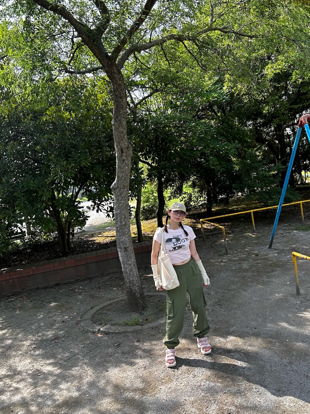 グリーン系のカーゴパンツ、ピンク系のTシャツ/カットソー、ホワイト系のサンダルを着用したレディースの夏コーディネートの2枚目の写真