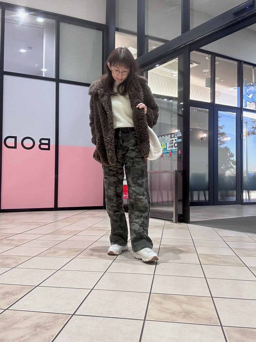 ホワイト系のトートバッグ、ホワイト系のスニーカー、ブラウン系のその他アウターを着用したレディースの冬コーディネートの2枚目の写真