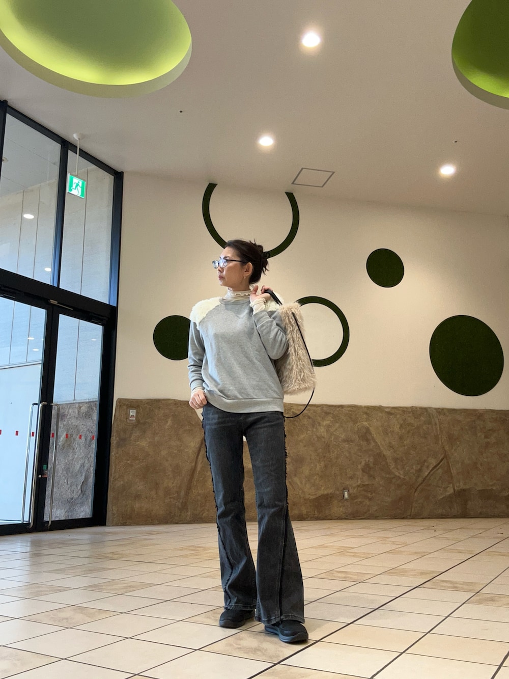 ブラウン系のダウンベスト、ベージュ系のトートバッグ、ブラック系のデニムパンツを着用したレディースの秋コーディネートの2枚目の写真