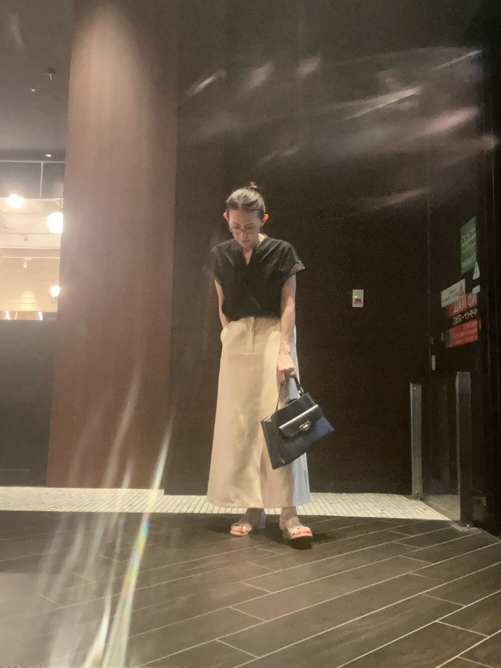 ブラック系のTシャツ/カットソー、ブラック系のハンドバッグ、ゴールド系のスカートを着用したレディースの夏コーディネートの2枚目の写真