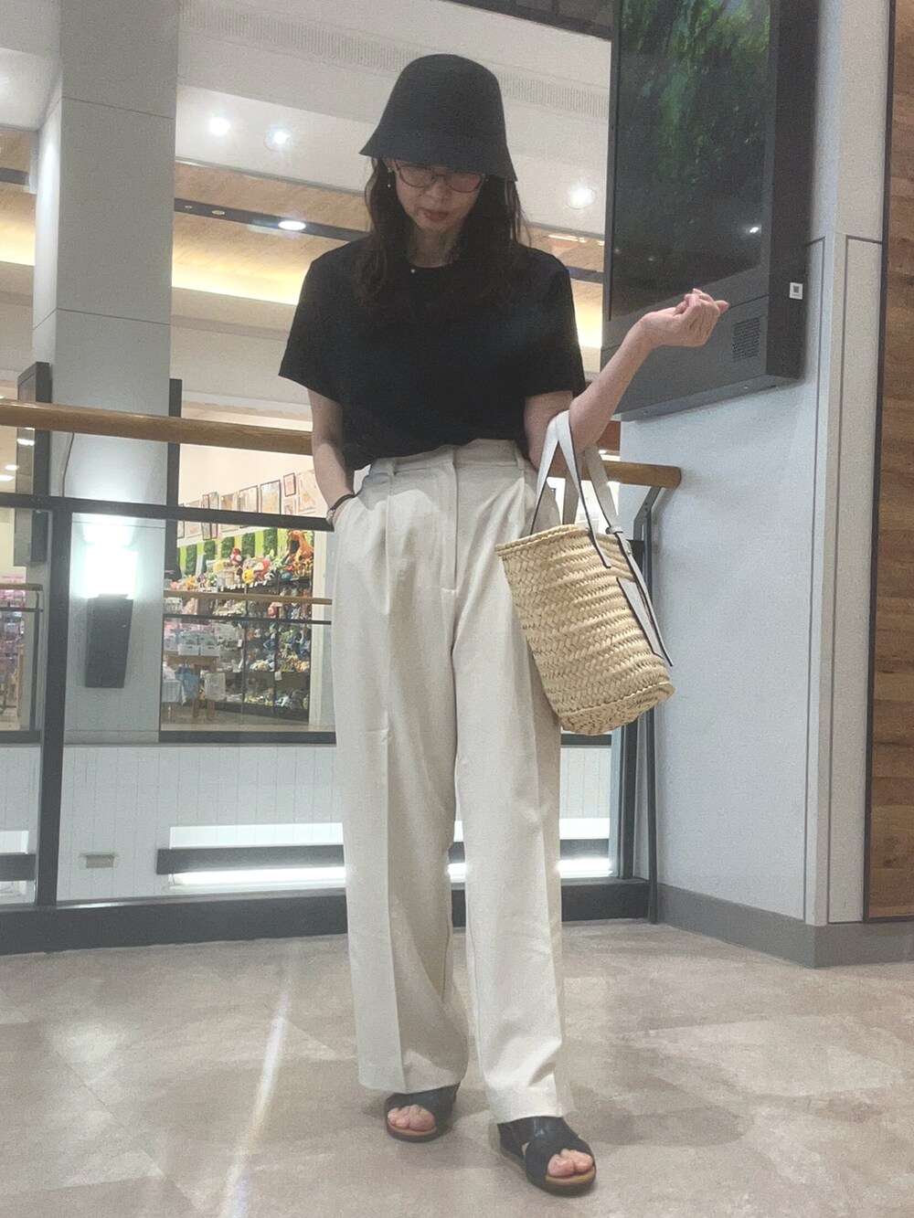 ホワイト系のかごバッグ、ホワイト系のスラックス、ブラック系のTシャツ/カットソーを着用したレディースの春コーディネートの2枚目の写真