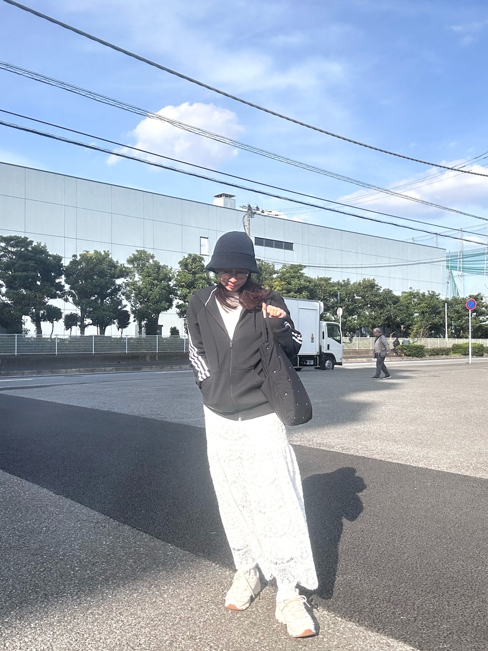 ホワイト系のスカート、ブラック系のトートバッグ、ブラック系のパーカーを着用したレディースの春コーディネートの2枚目の写真