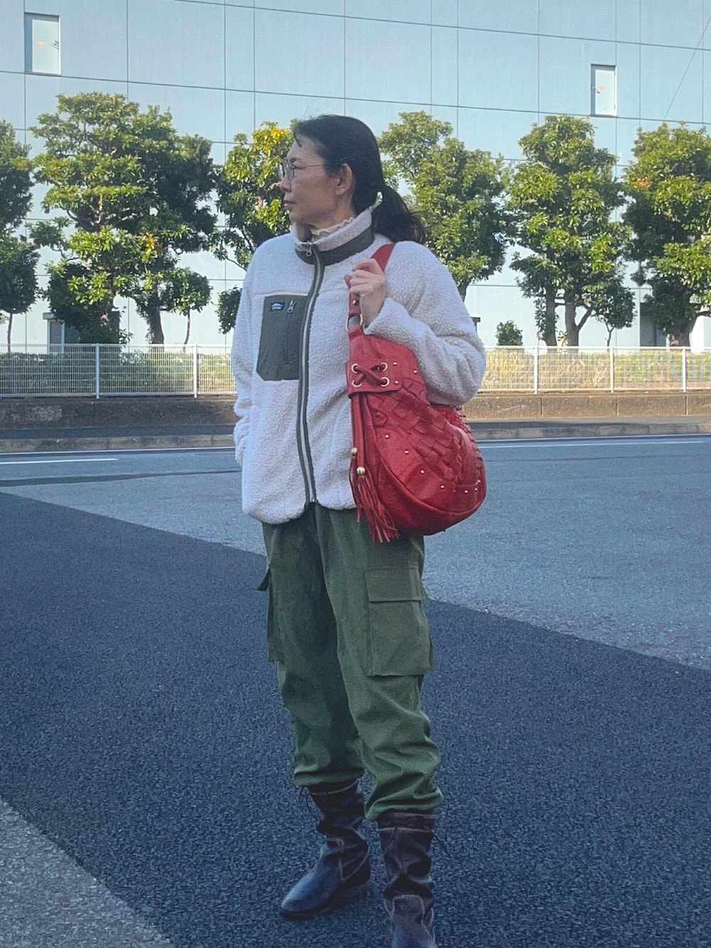 オレンジ系のニット/セーター、ブラウン系のブーツ、ベージュ系のその他アウターを着用したレディースの春コーディネートの2枚目の写真