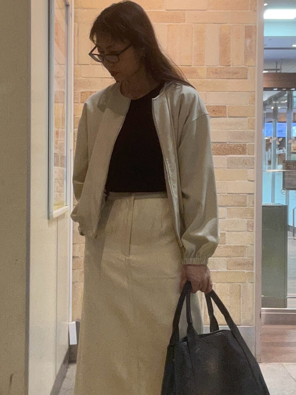 ホワイト系のスカート、ブラック系のシューズを着用したレディースの春コーディネートの2枚目の写真