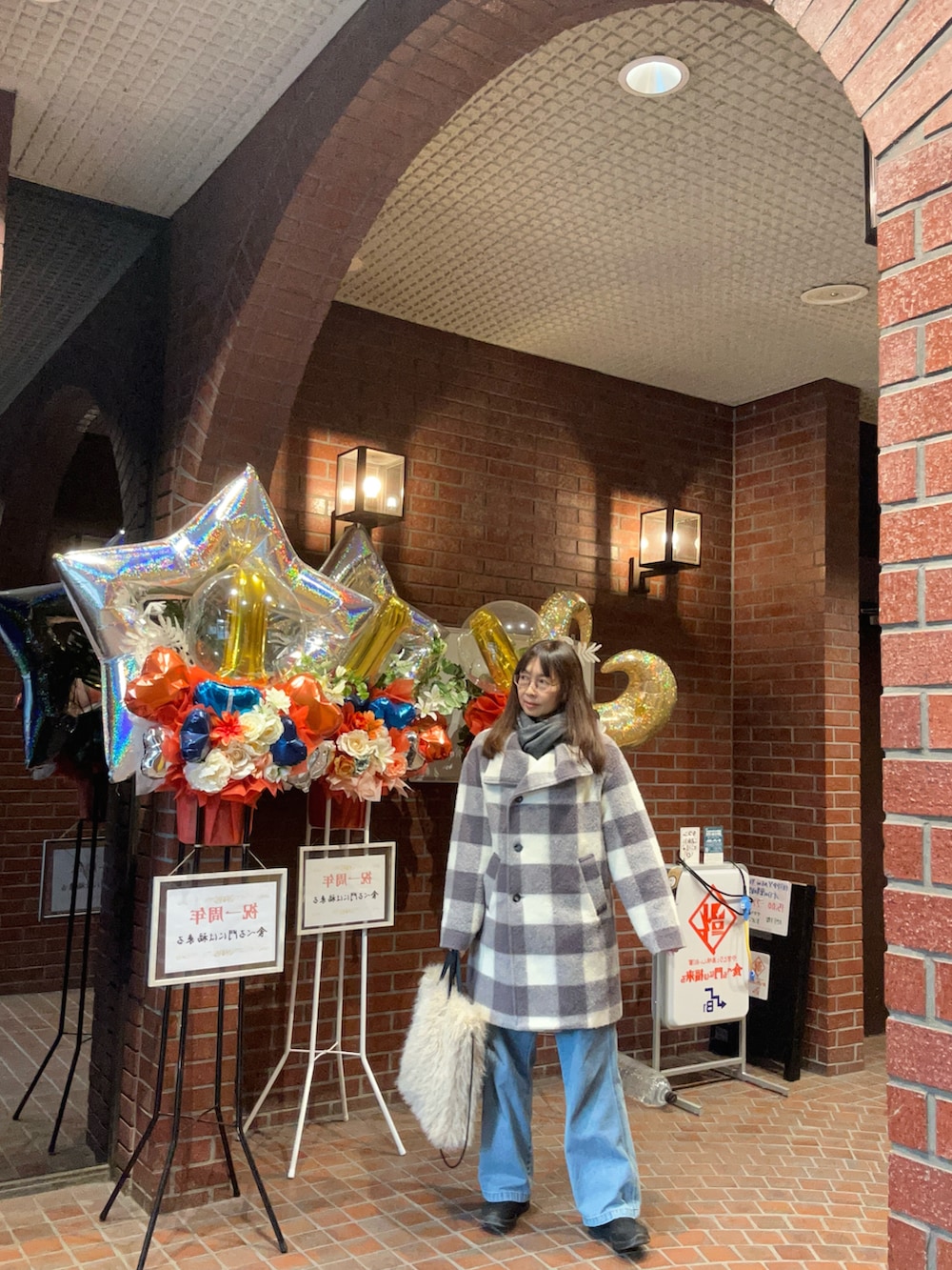 グレー系のステンカラーコート、ブルー系のデニムパンツ、グレー系のマフラーを着用したレディースの冬コーディネートの2枚目の写真