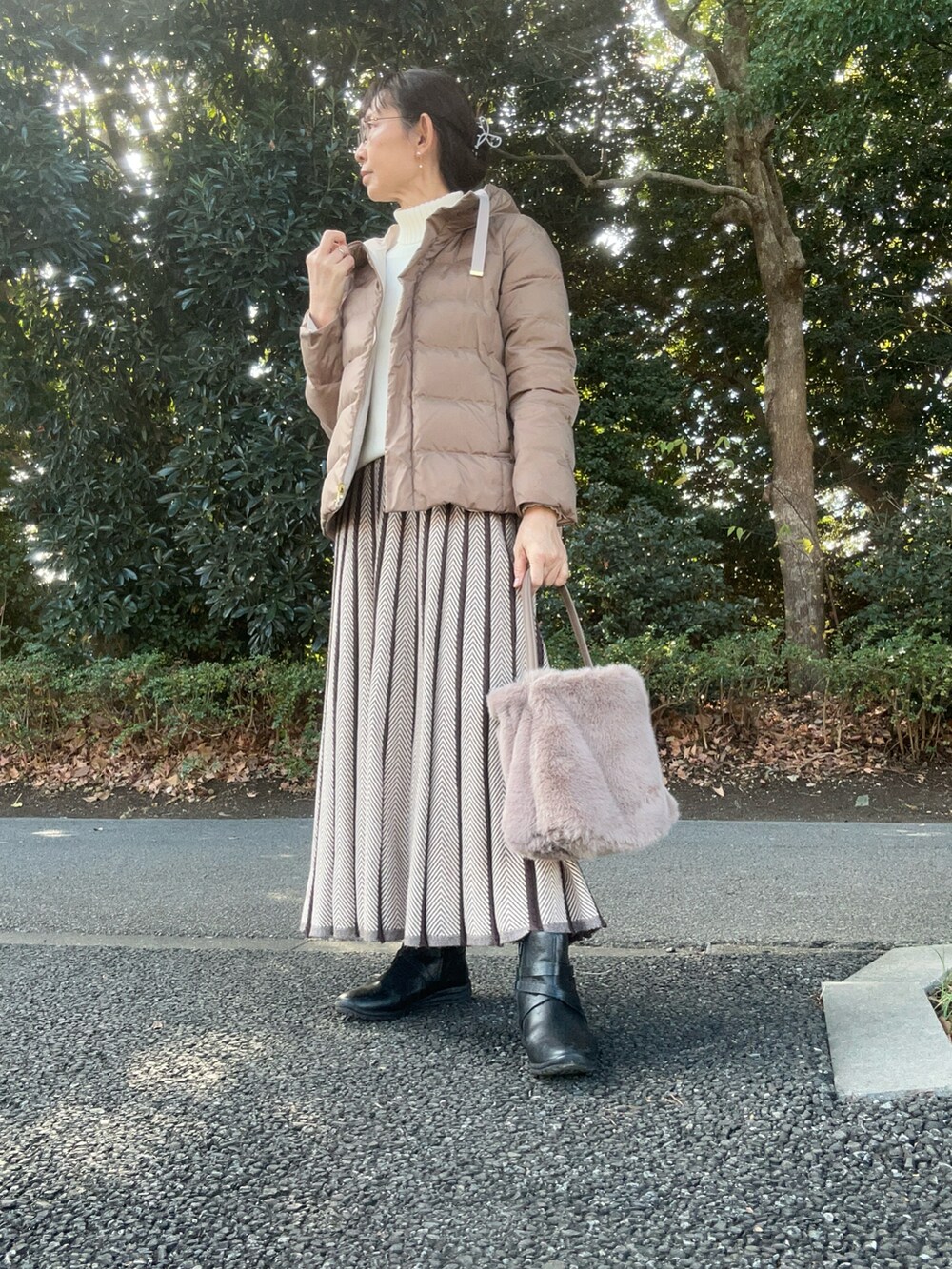 ベージュ系のハンドバッグ、ベージュ系のダウンジャケット/コート、ブラック系のブーツを着用したレディースの冬コーディネートの2枚目の写真