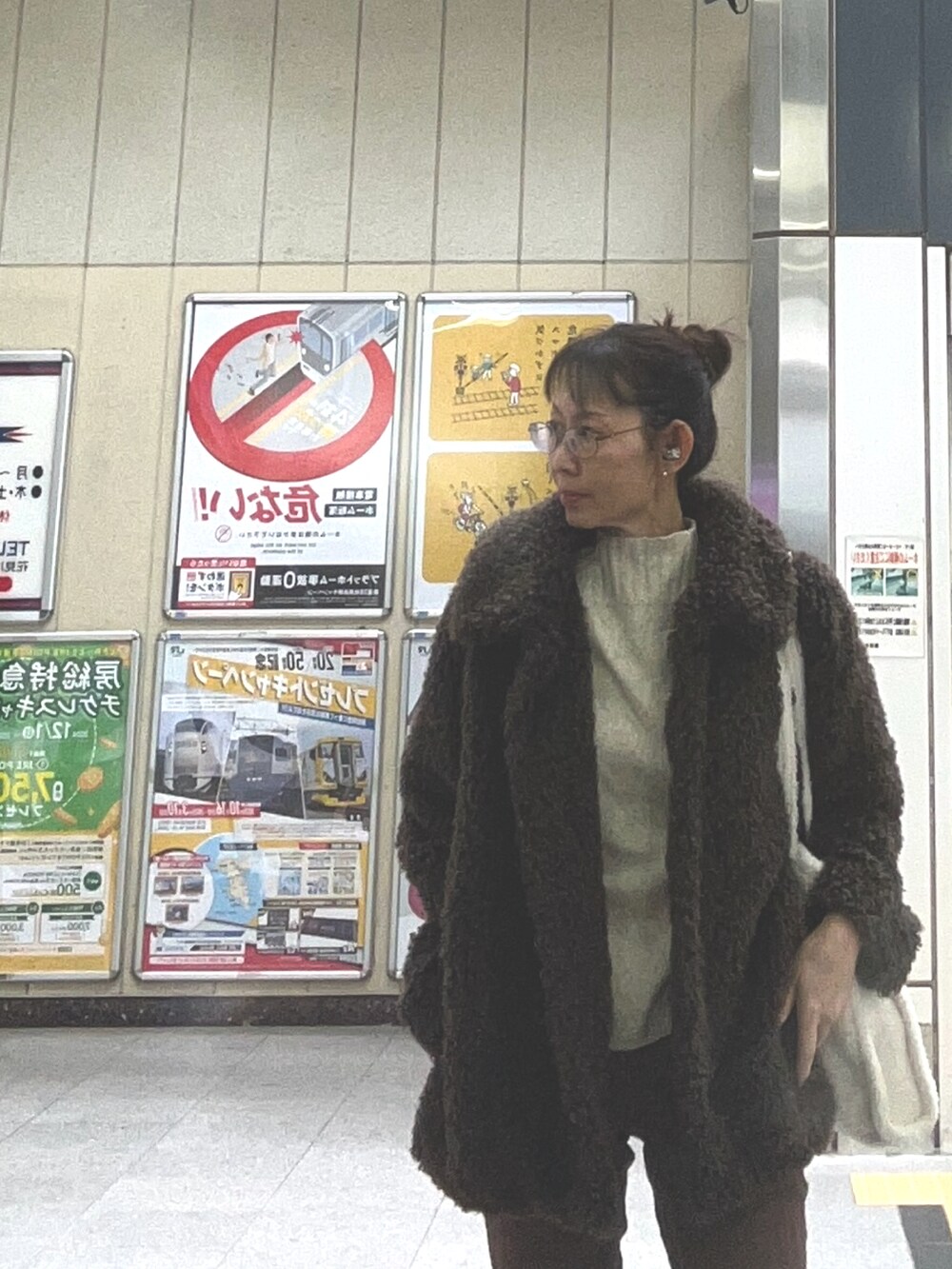 ブラウン系のデニムパンツ、グリーン系のブーツ、ホワイト系のトートバッグを着用したレディースの冬コーディネートの2枚目の写真